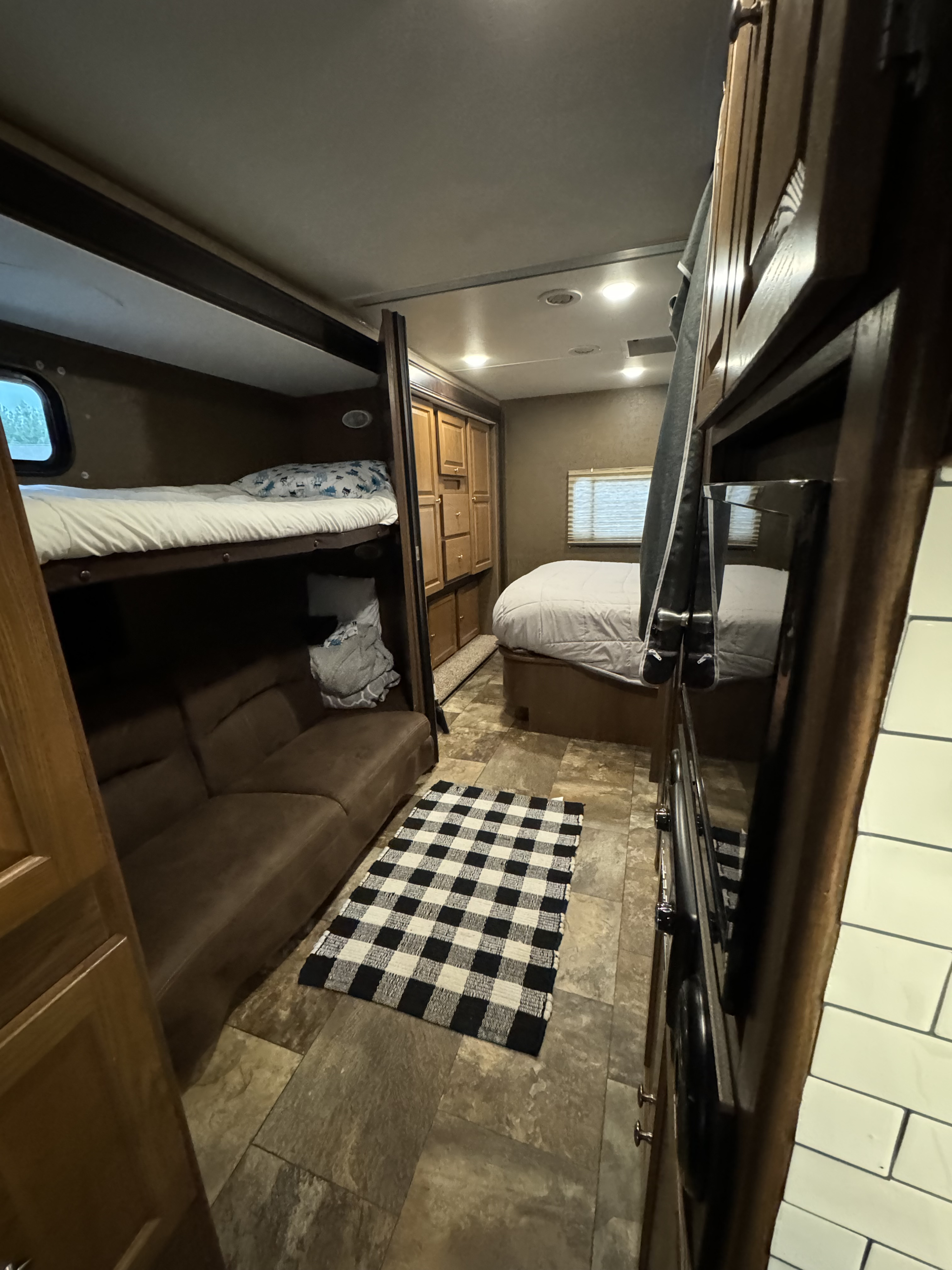 Spacious RV rental interior featuring a main bed, bunk beds, sofa, and media center, perfect for family adventures.. Coachmen 310BH Ford 450 Leprachaun 2017
