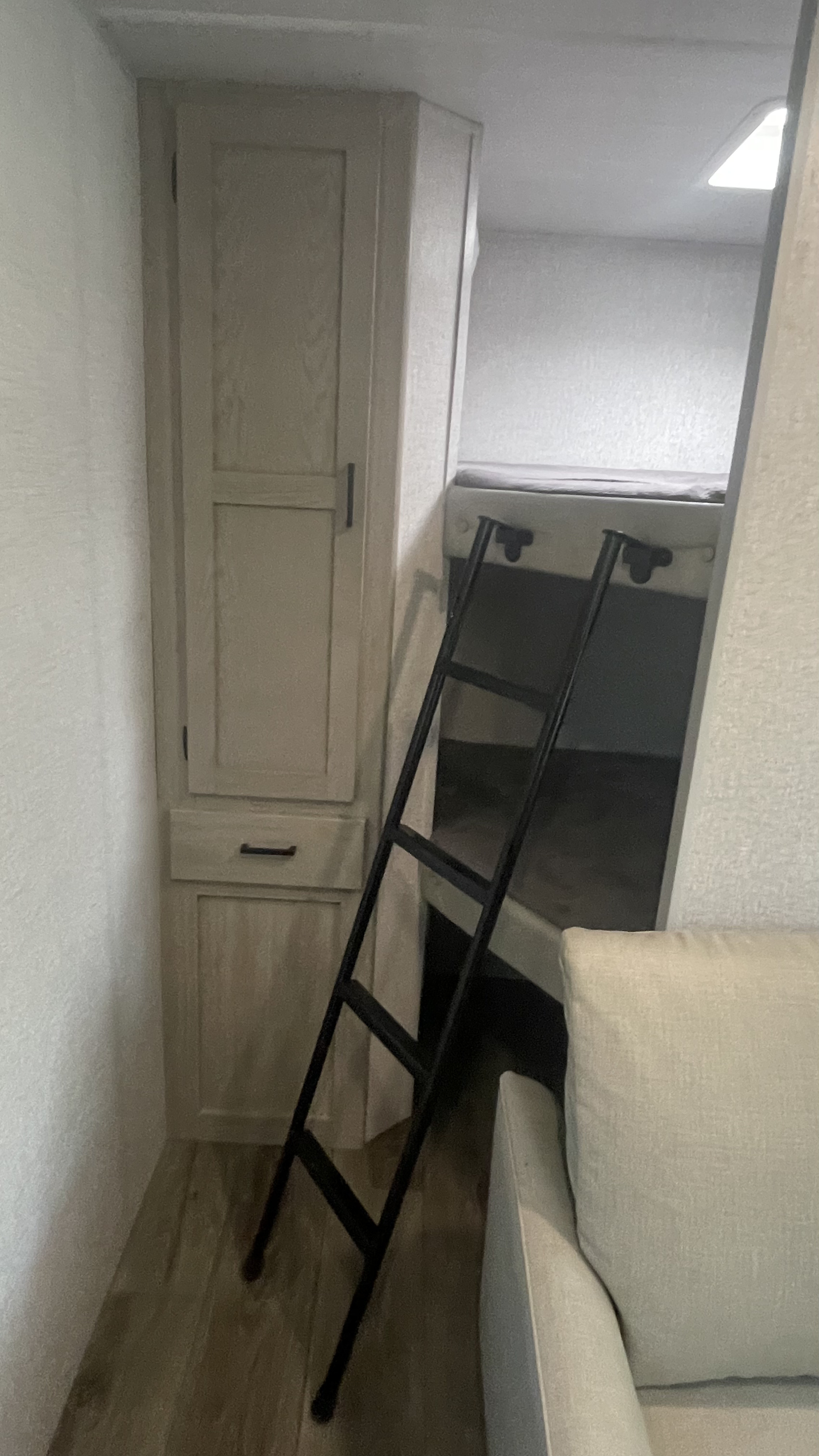 This RV rental's interior features bunk beds with a ladder, adjacent storage cabinets, and a comfy sofa.. East to West Alta 2022