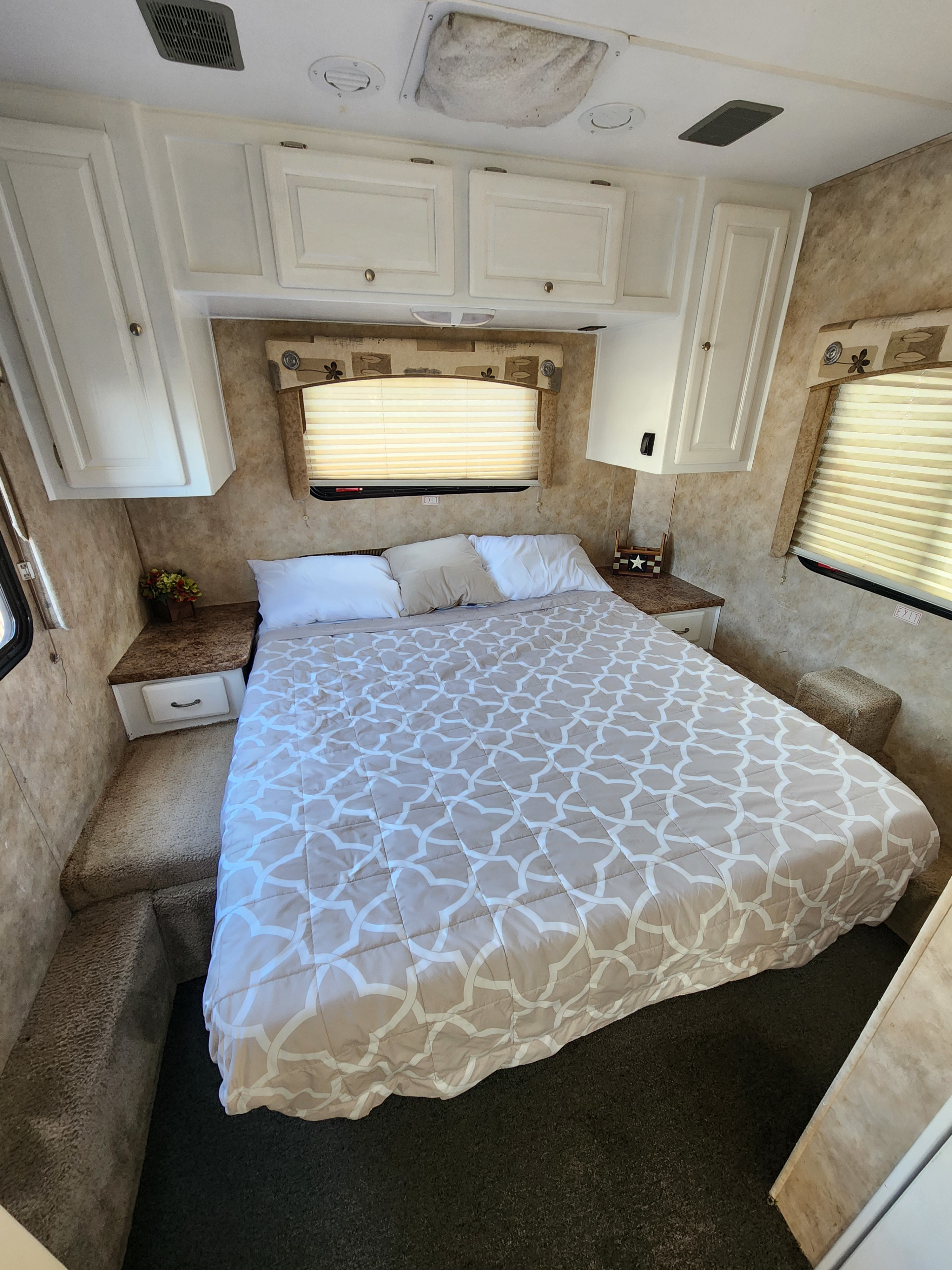 This cozy RV rental bedroom features a comfortable queen bed with a patterned comforter, overhead storage cabinets, and bedside tables.. Gulf Stream Conquest Ultra 2009