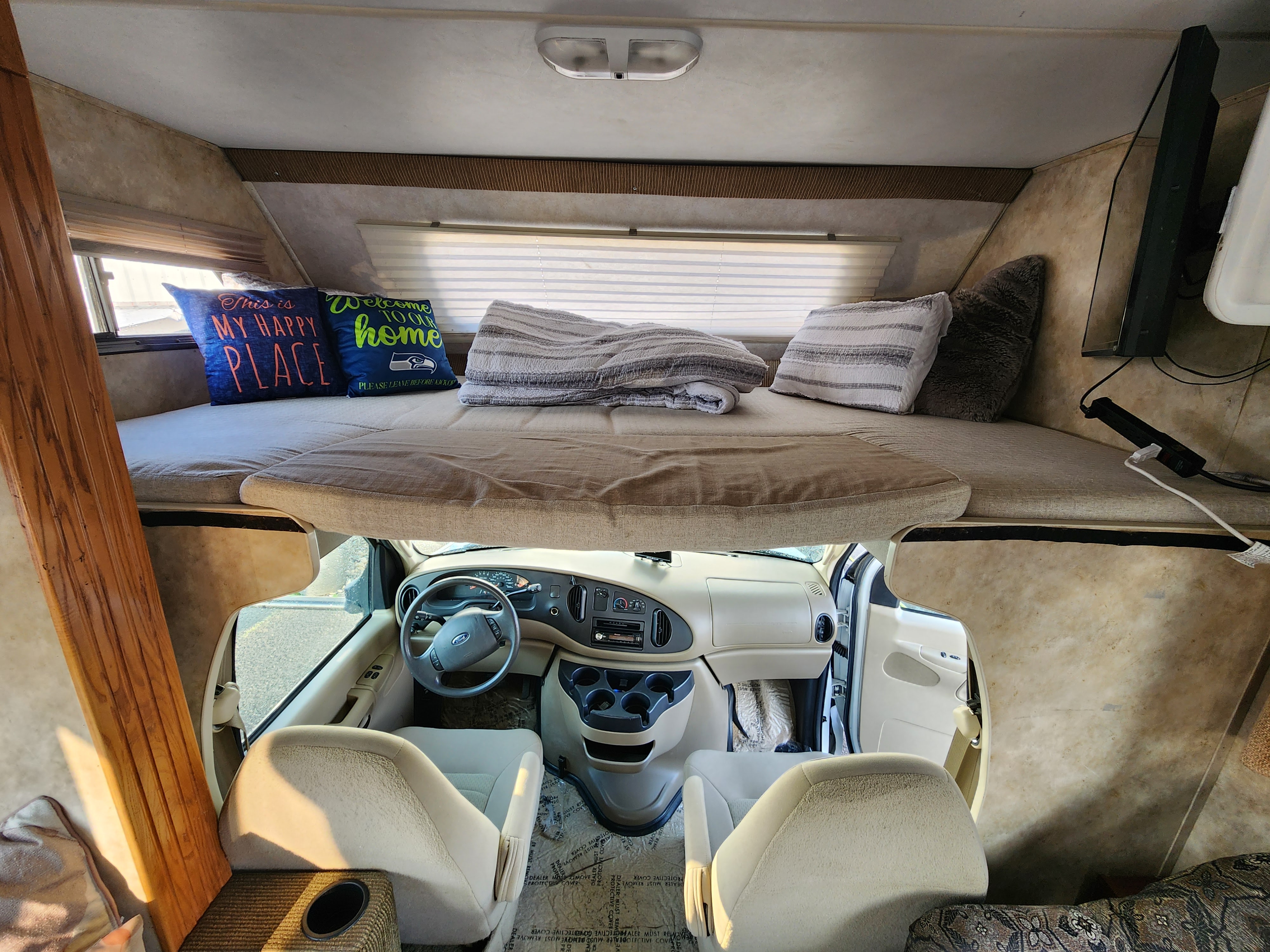 Inside this rv rental, a comfortable overhead bed with pillows and blankets sits above the spacious cockpit.. Gulf Stream Conquest Ultra 2009