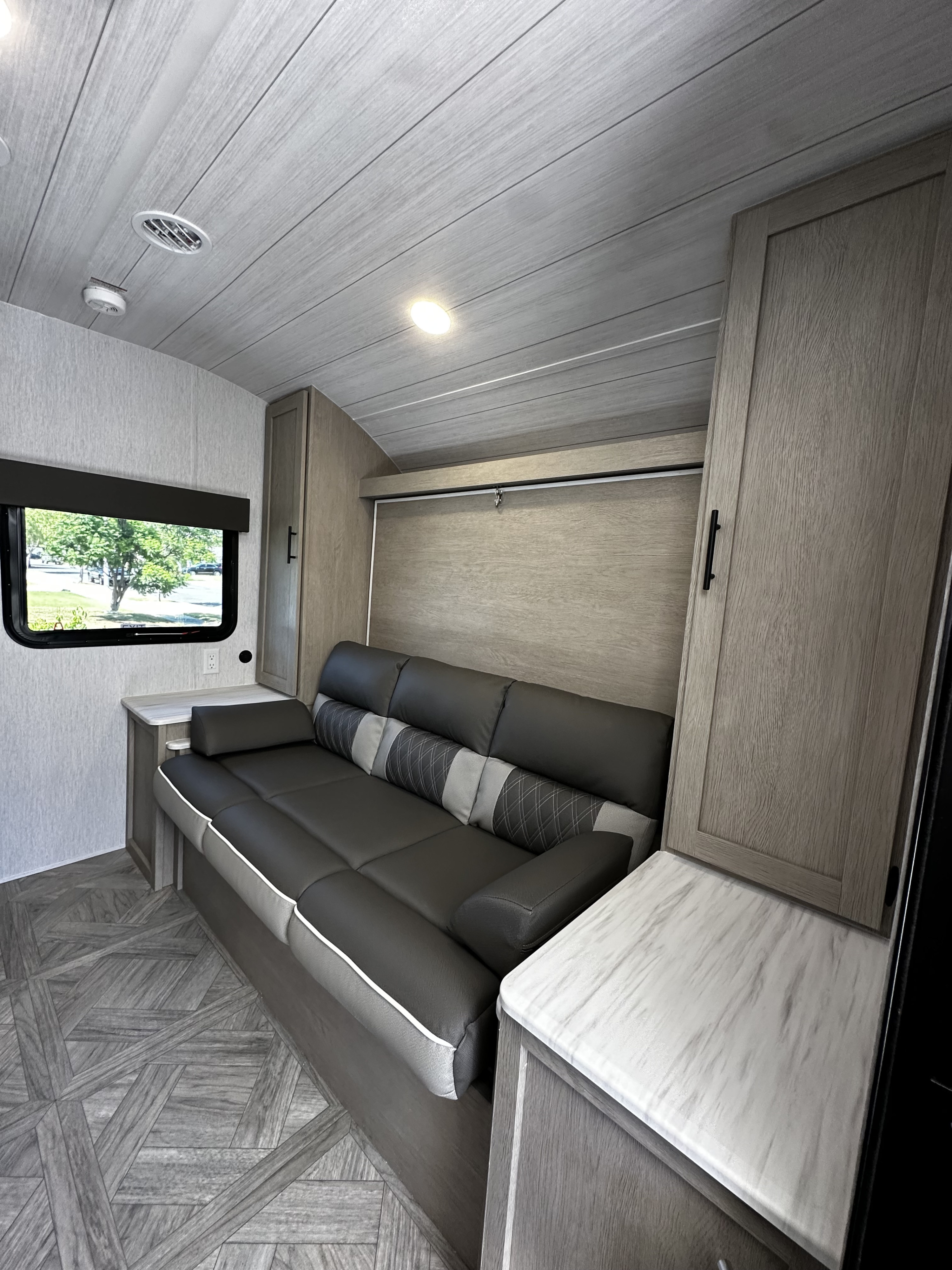 Modern RV rental interior featuring a comfortable sofa, convertible bed, and light wood finishes.. Forest River EVO 2024