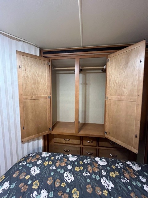 Open closet and drawers for storage in an RV rental bedroom, with hanging rods visible inside.. Winnebago Minnie Winnie 2017