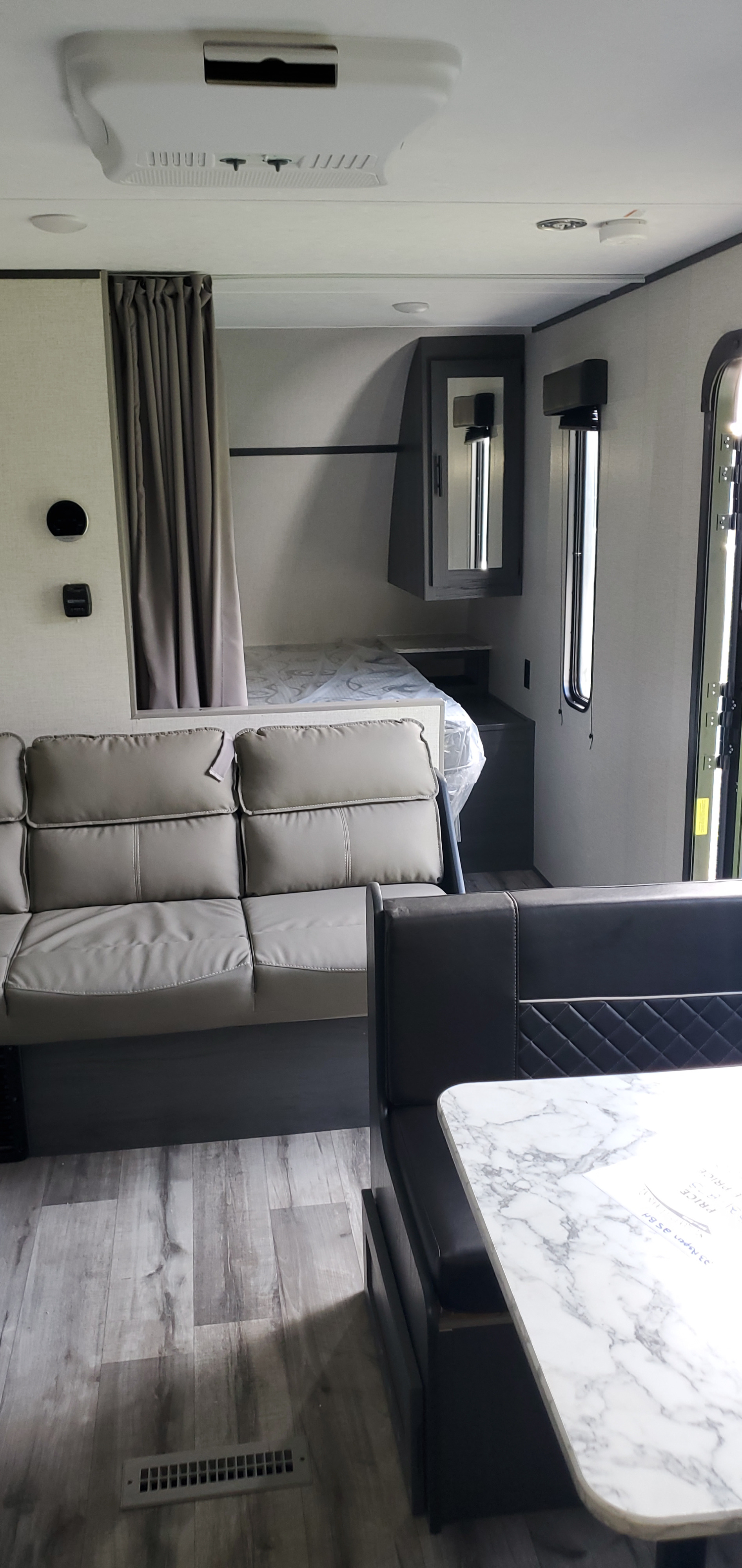 Modern rv rental interior: living space with sofa, dinette, and cozy sleeping nook with privacy curtain.. Aspen Trail LE 2023