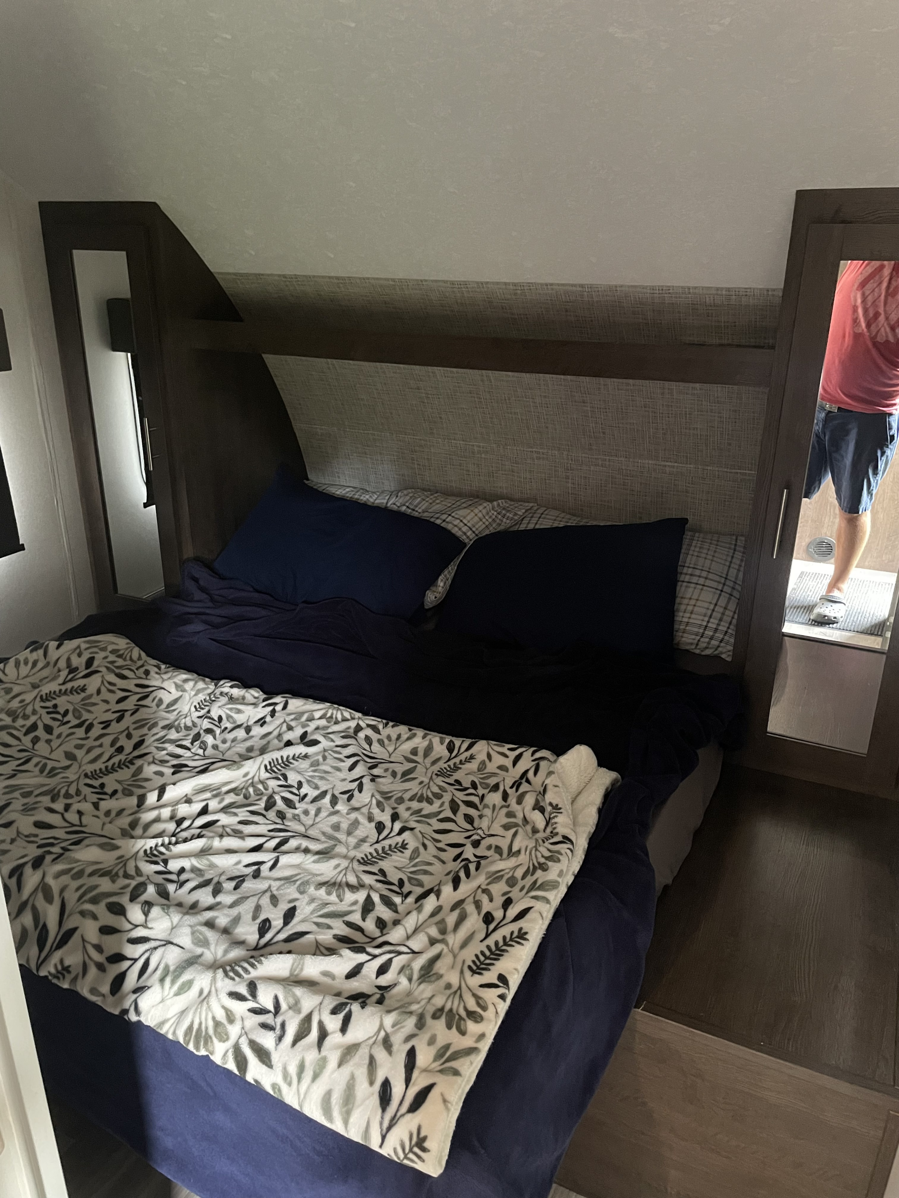 Inside this RV rental, a compact bedroom features a bed with blue sheets, a leaf-patterned blanket, and mirrored door.. Forest River Salem Cruise Lite 2020