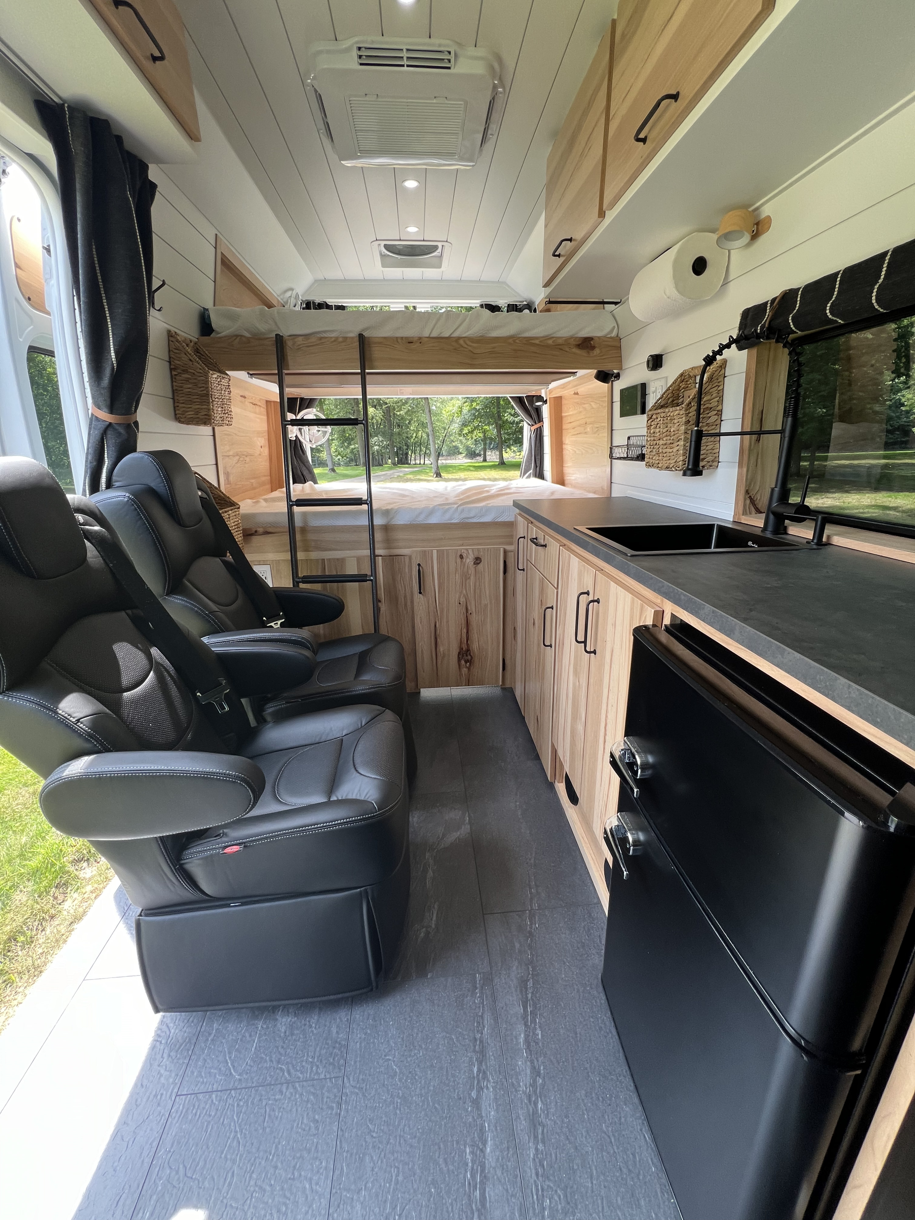 Spacious RV rental interior: bunk beds, kitchen, & comfy black leather captain's chairs. Ready for adventure.. Ram Promaster Super High Roof 2024