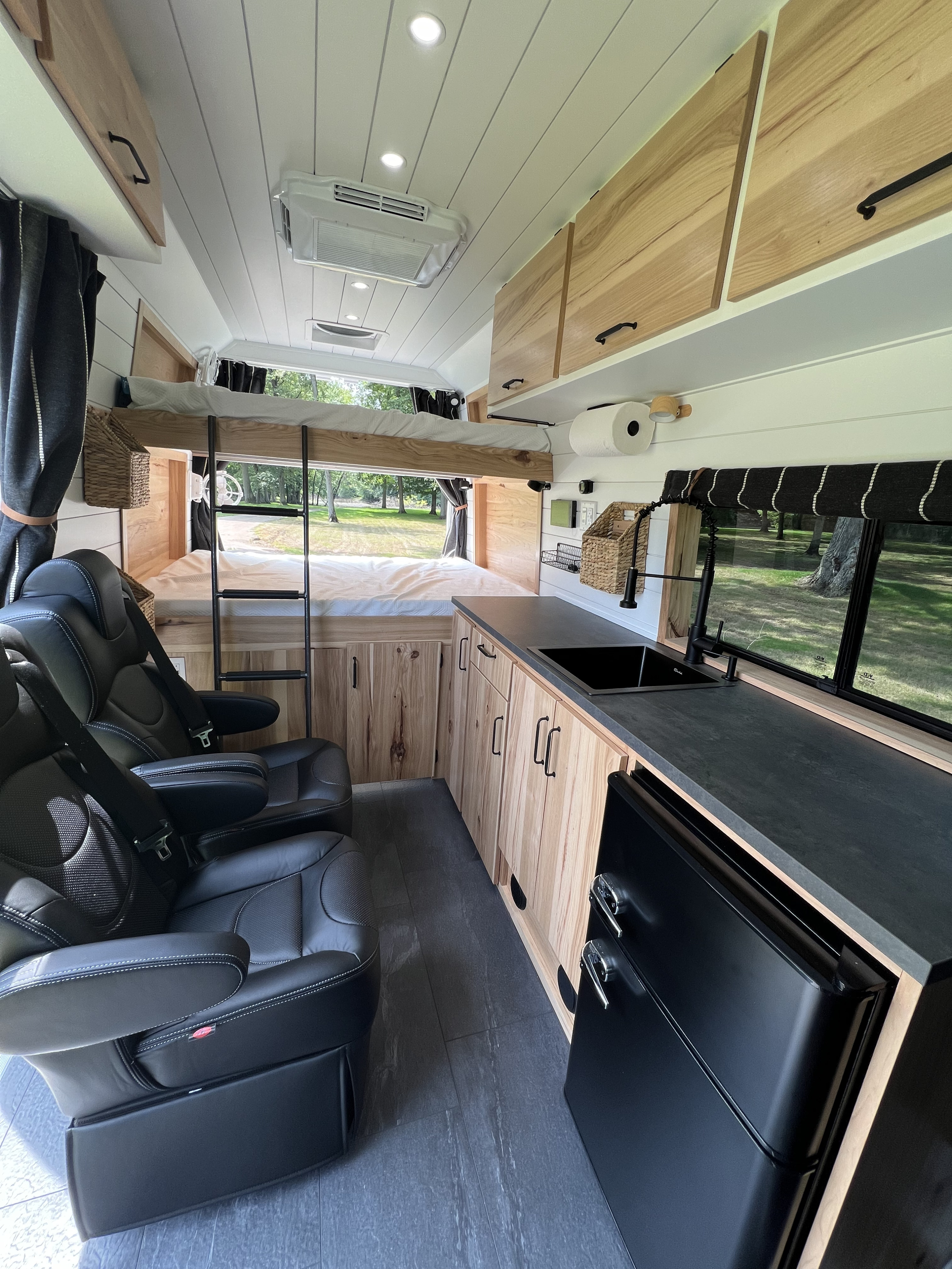 RV rental interior showcases a modern design with bunk beds, kitchen, comfy seating, and light wood cabinets, ideal for travel.. Ram Promaster Super High Roof 2024