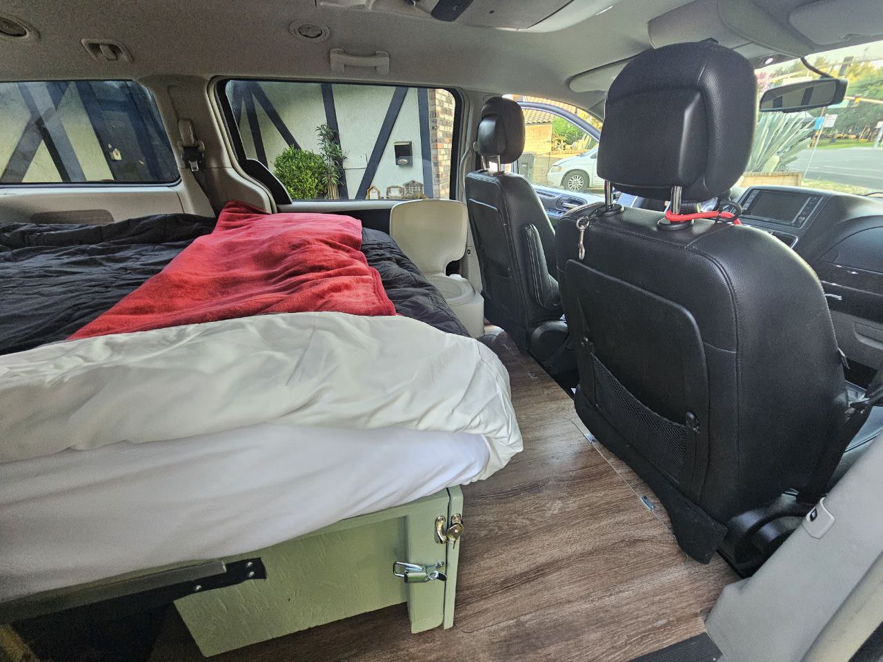 Minivan interior transformed into a camper, with a bed setup, storage, and wood floor. Great RV rental option.. Chrysler Town Country 2014