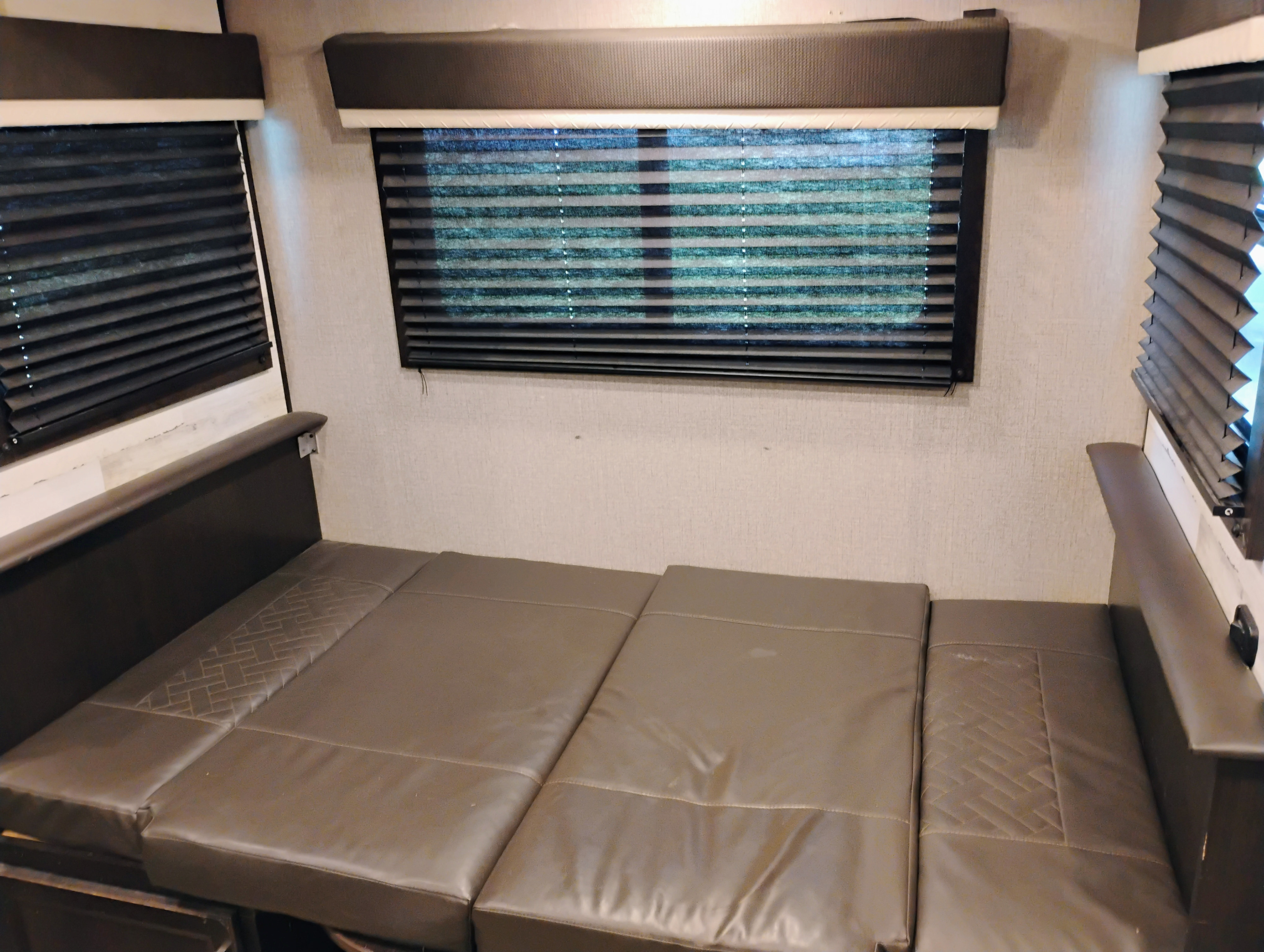 Comfortable RV rental interior with a flattened dinette bed and pleated window blinds, offering a cozy sleeping area.. Jayco Jay Feather 2021