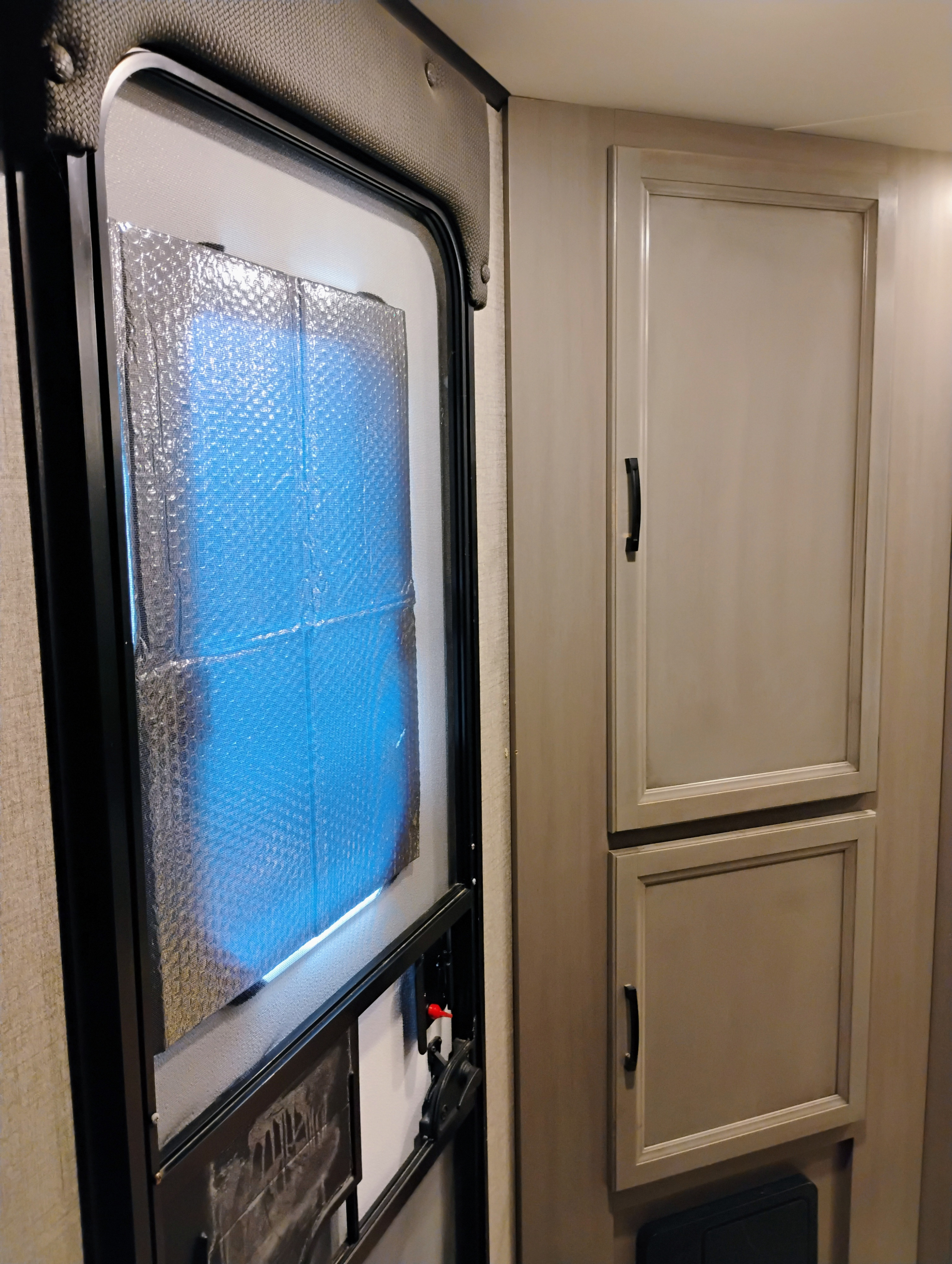 RV rental interior: window with reflective insulation and screen, next to light-colored storage cabinets.. Jayco Jay Feather 2021