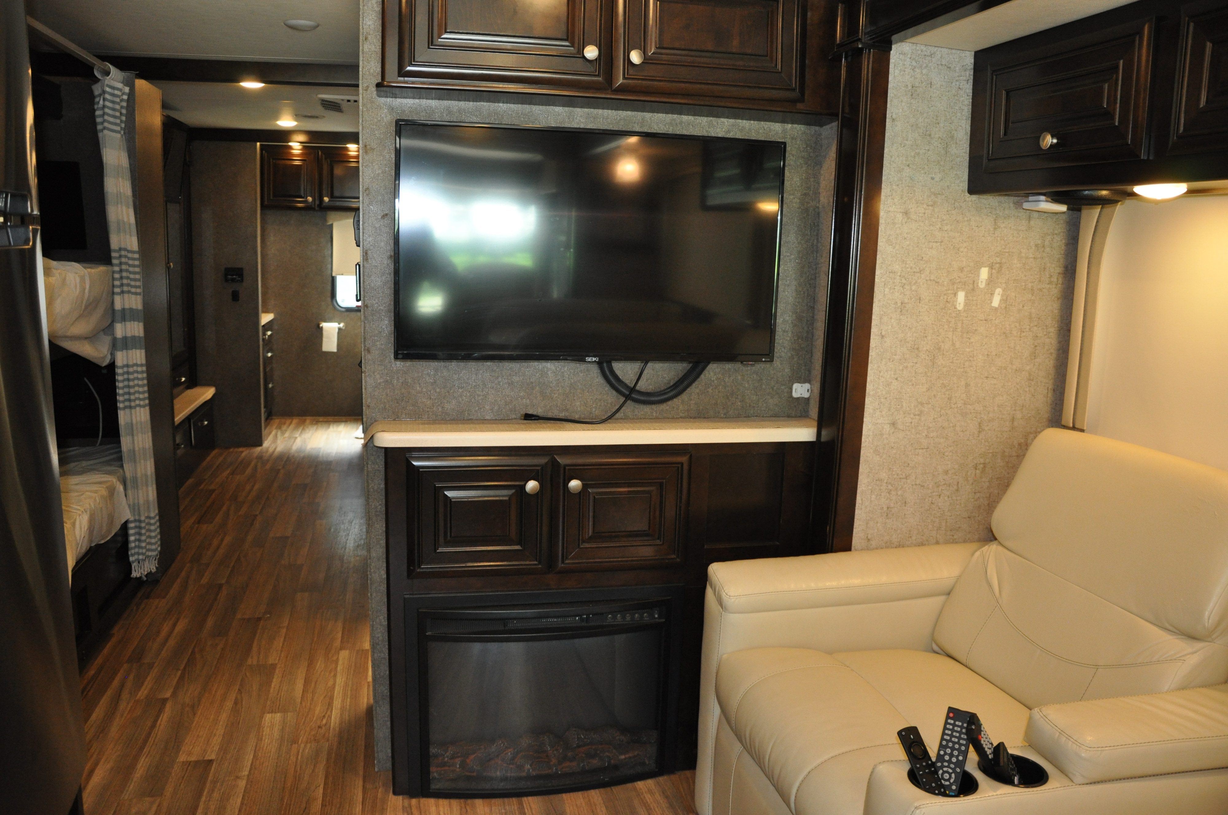 RV rental interior: living area with TV, electric fireplace, comfy recliner, and bunk beds. Ideal for road trips.. Thor Motor Coach Miramar 2017