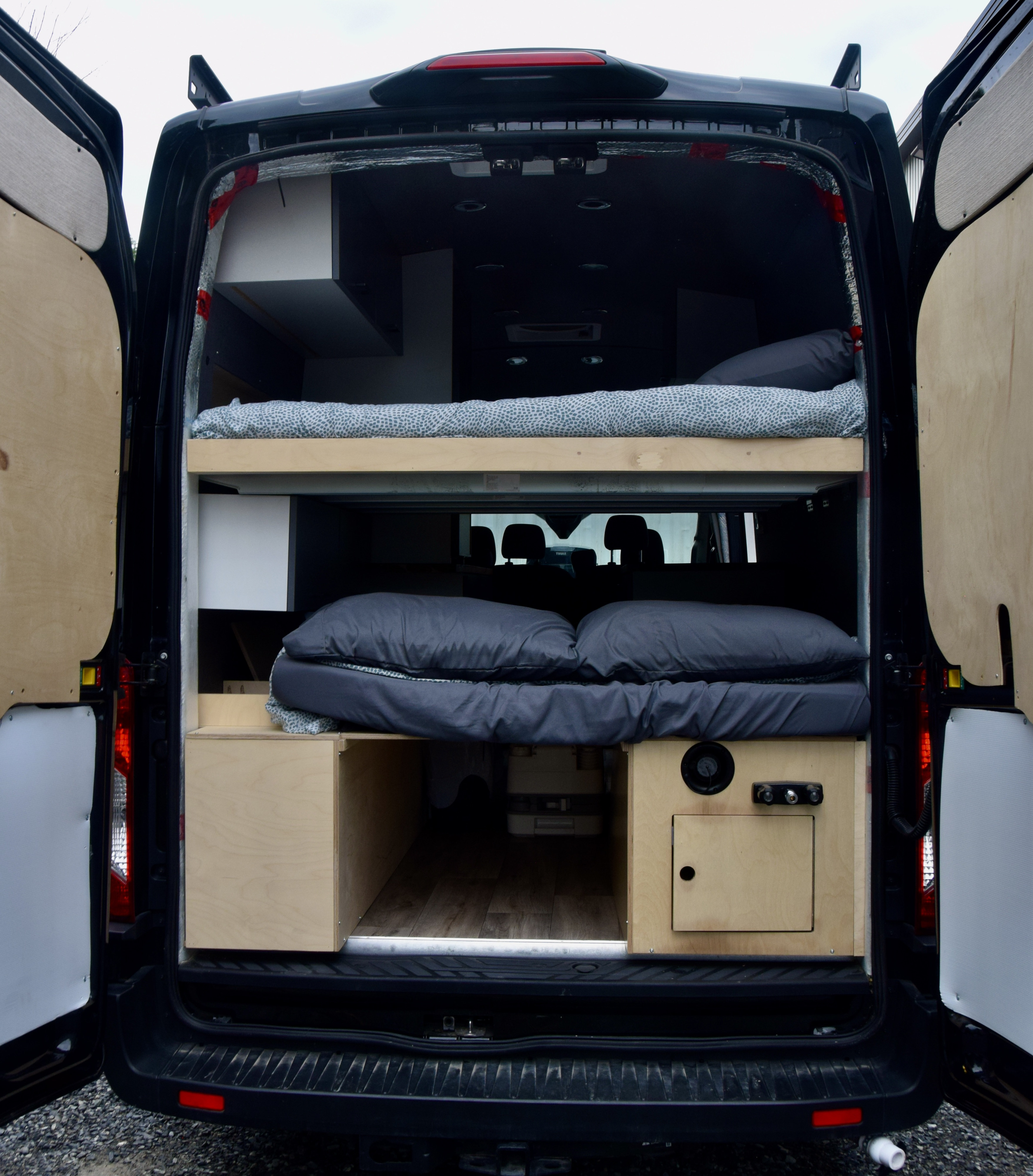 Inside this RV rental: a custom camper van interior with bunk beds, storage, and a portable toilet.. Ford Van 2023
