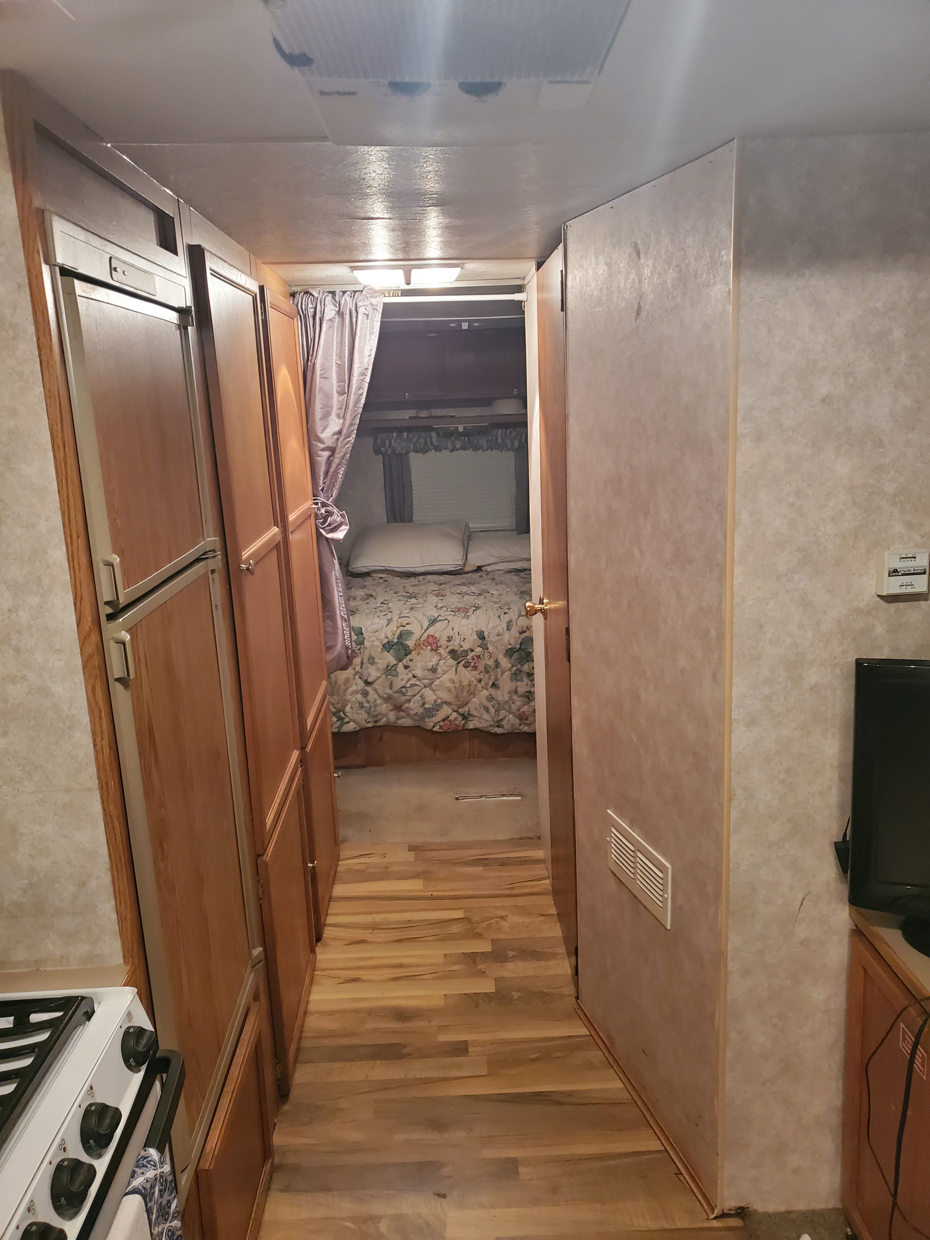 RV rental interior: View of the hallway, leading past the kitchen/fridge to a cozy bedroom.. R-Vision Trail-Lite 2000