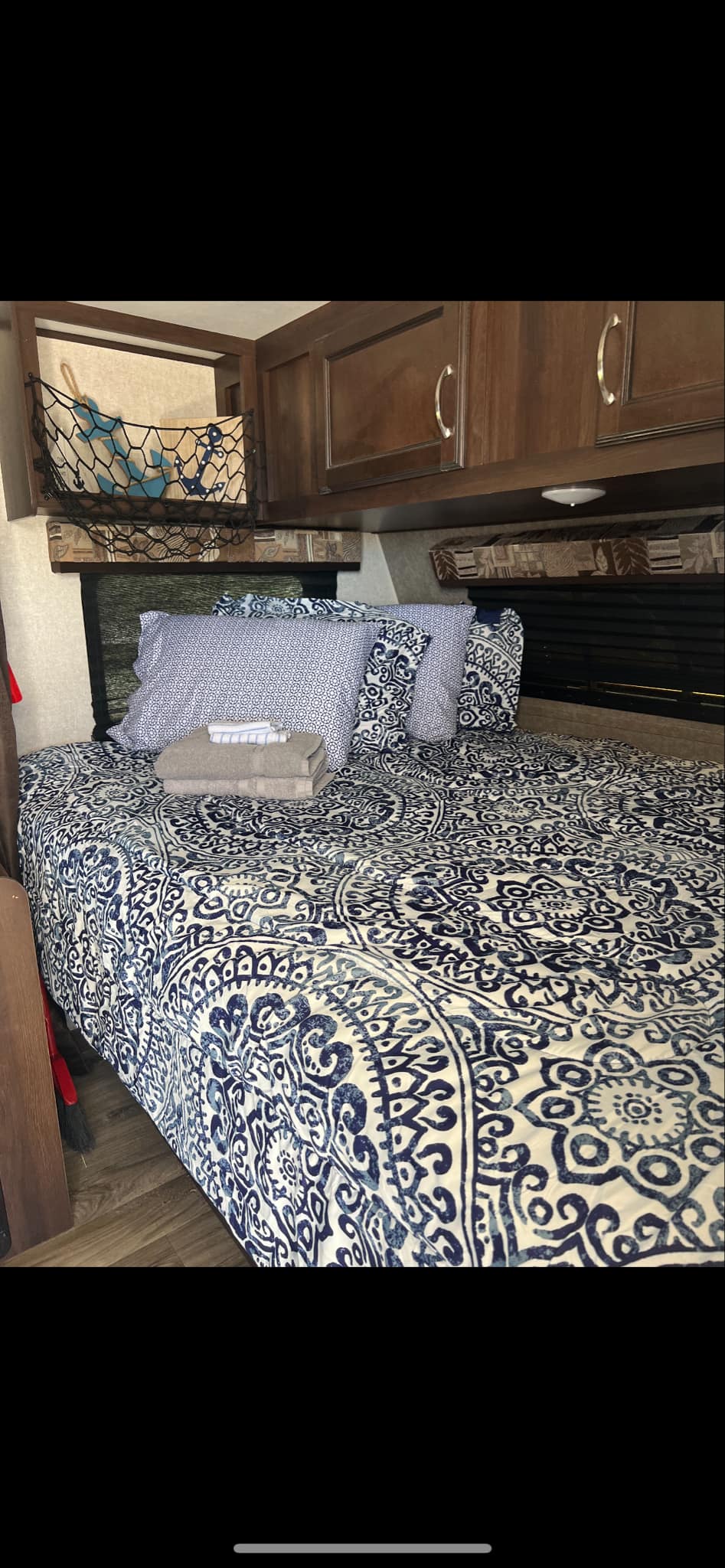 RV rental bedroom with a cozy bed featuring blue patterned bedding, overhead storage, and fresh towels for your comfort.. Jayco Jay Flight 2018