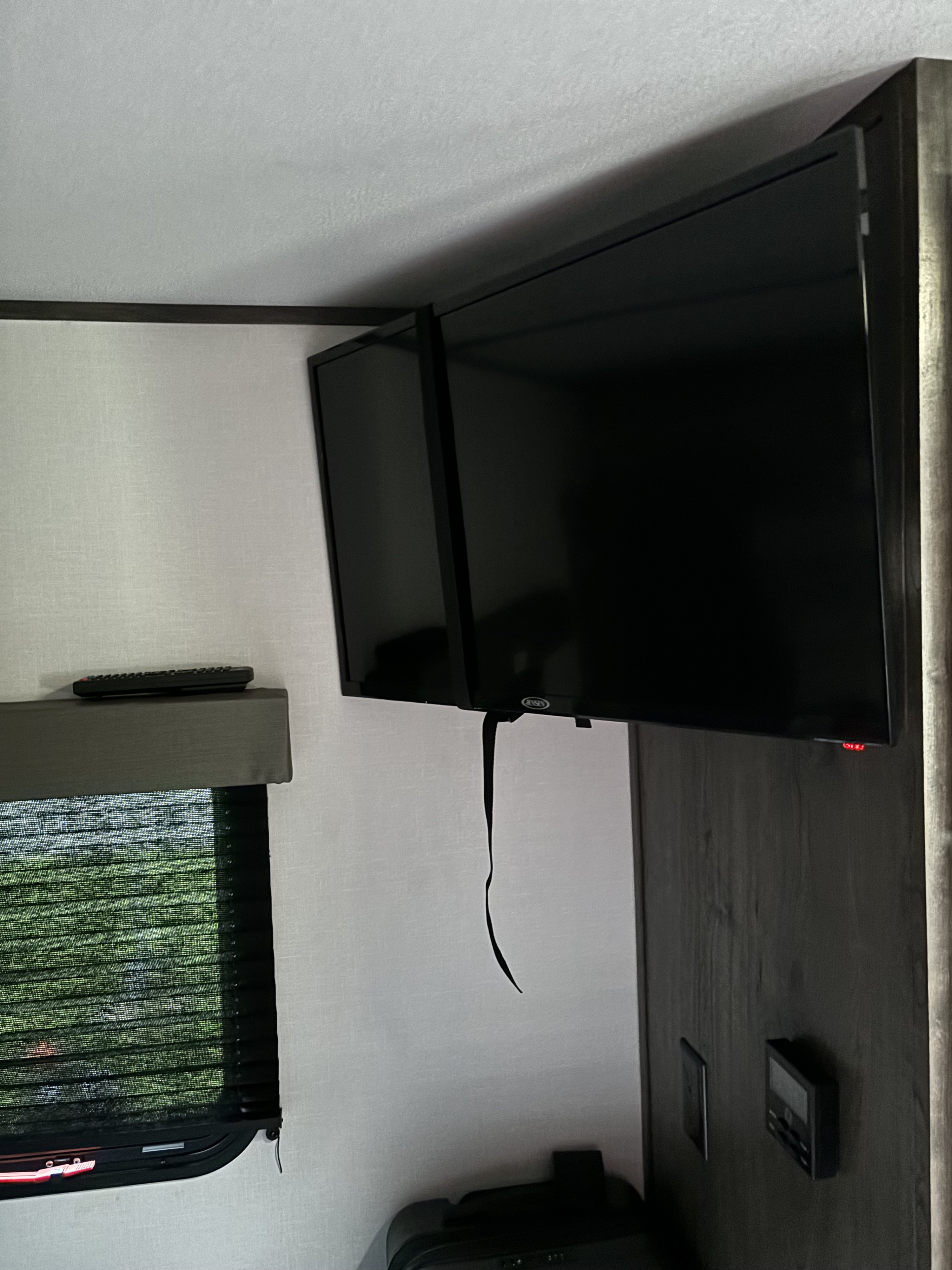 Inside an RV rental: Dual mounted TVs, remote, and window shade. Compact entertainment for travel.. Riverside RV Retro 2022