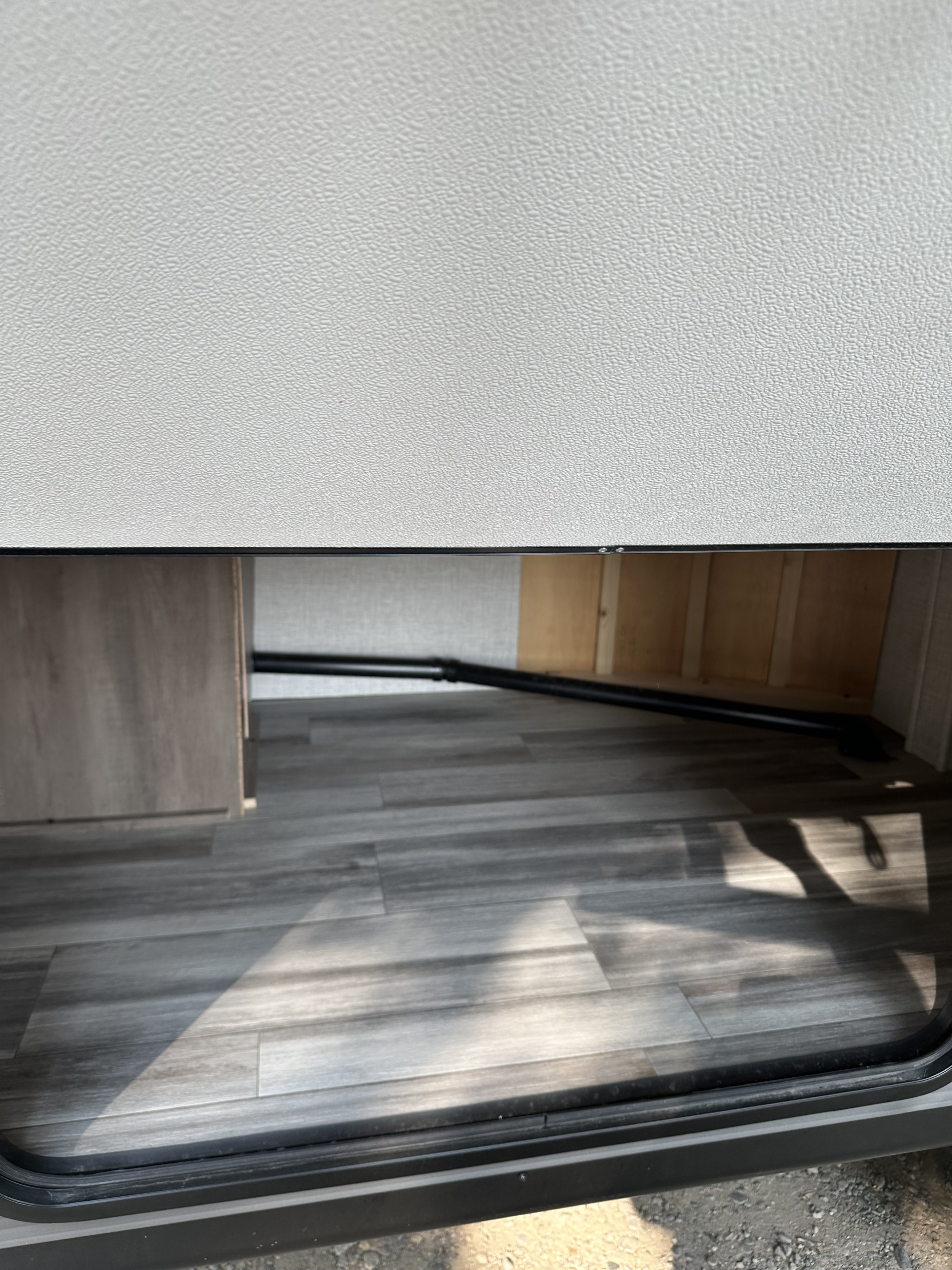 RV storage space with a grey wood-look floor and black pipe inside an rv rental, great for stowing gear.. Jayco Jay Flight SLX 2024
