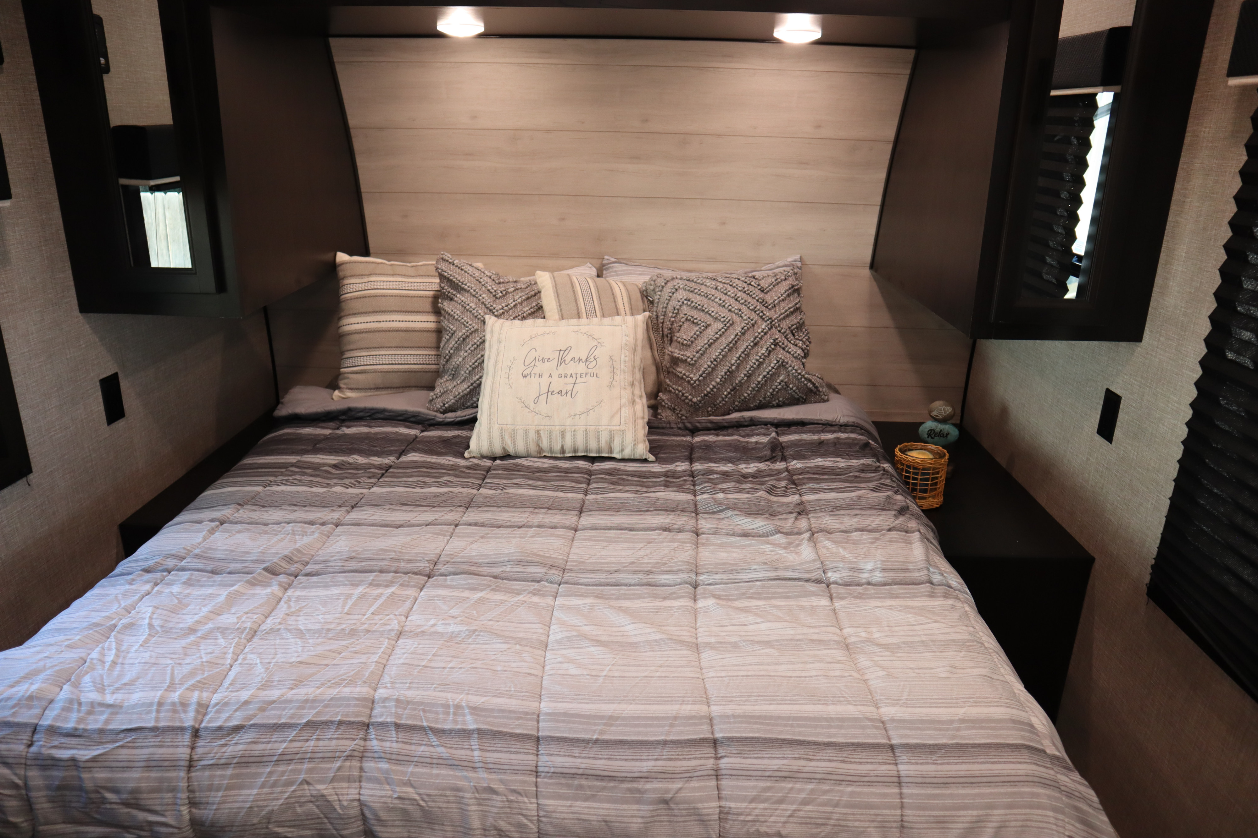 Cozy RV rental bedroom interior with a striped bed, decorative pillows, and built-in storage.. Jayco Jay Flight Baja Edition 2023