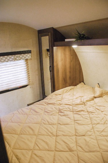 RV rental bedroom showcasing a comfortable bed, window with blinds, and built-in storage cabinets.. Connect Connect Trailer 2017