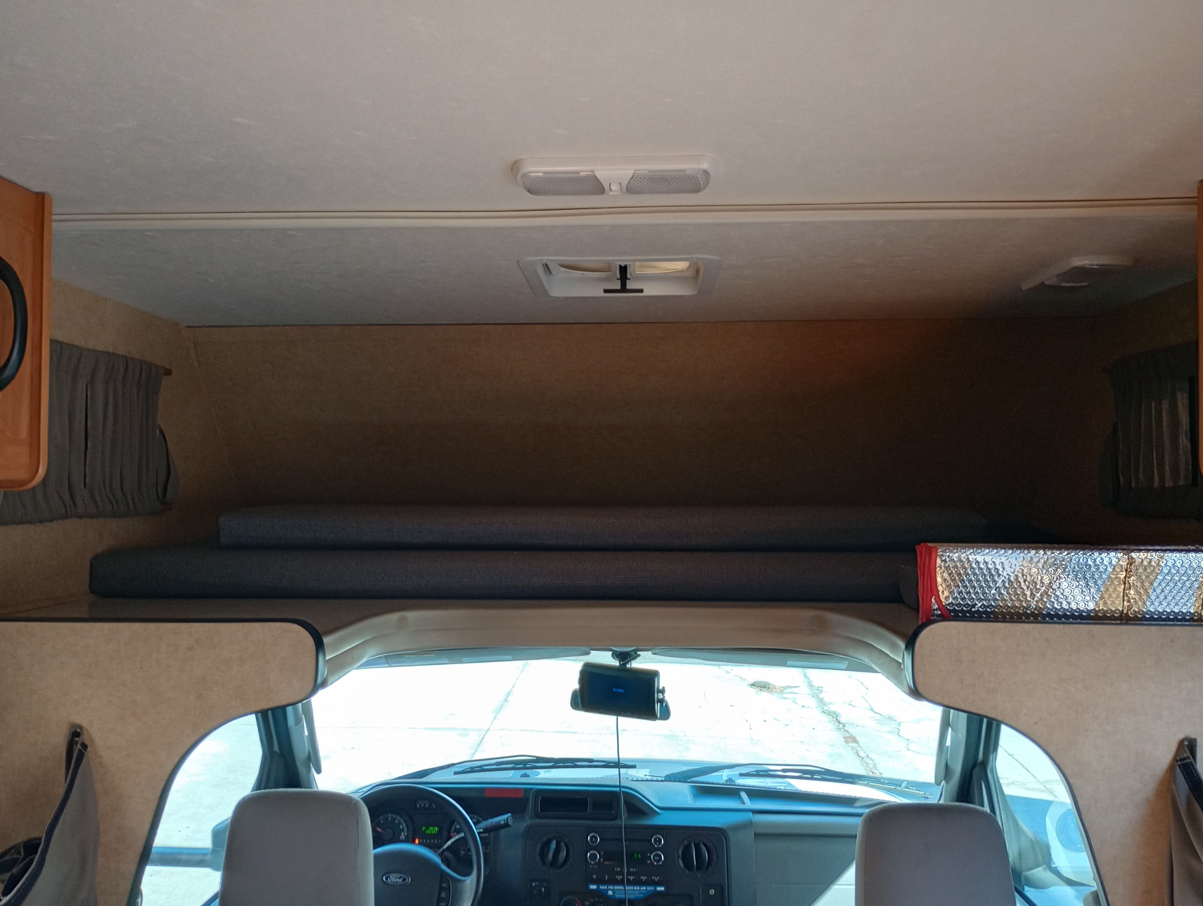 Inside an **rv rental**, showing the overhead bunk with cushions and the front cab with dashboard.. Ford Majestic 2019