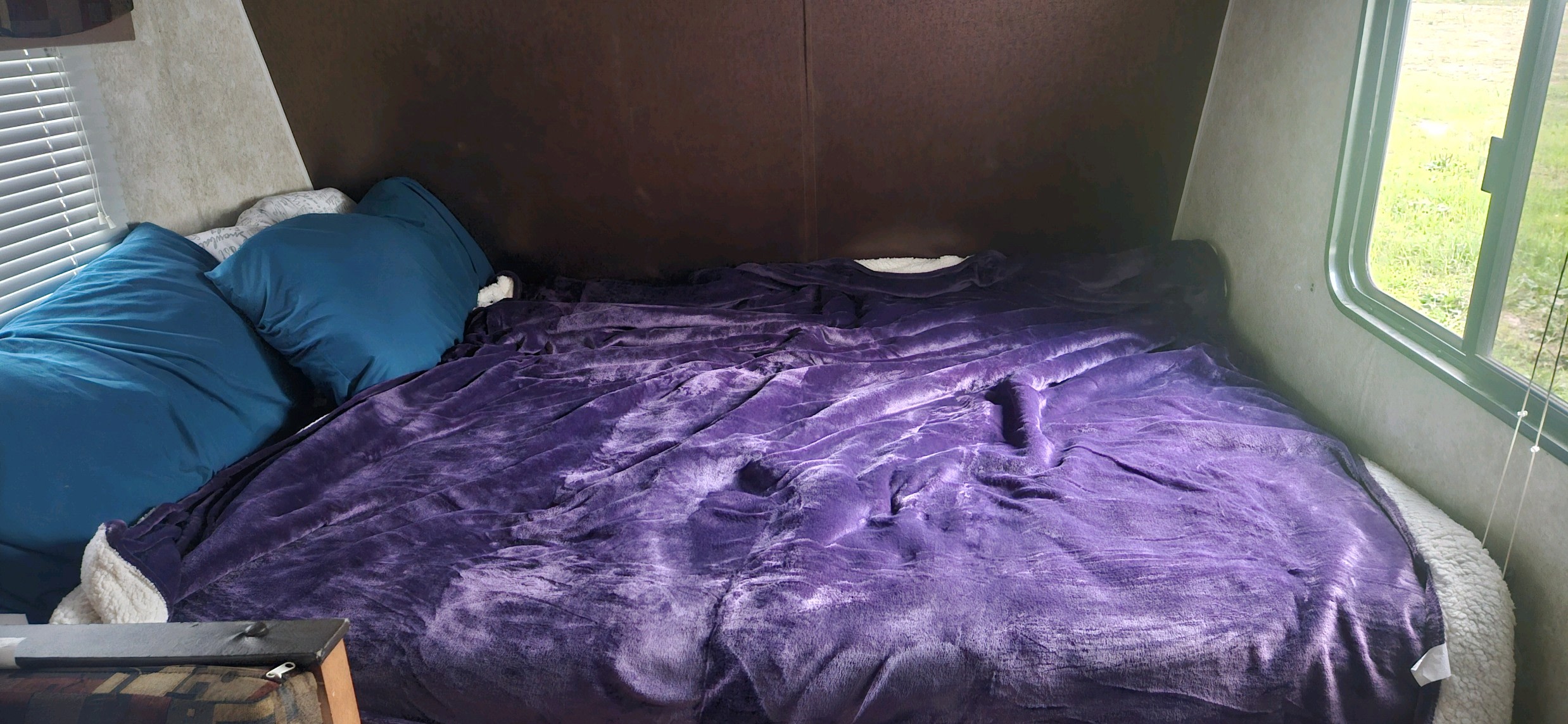 Cozy RV rental bedroom with blue pillows and a soft purple blanket, perfect for comfortable travel adventures.. Gulf Stream Ameri-Lite 2018