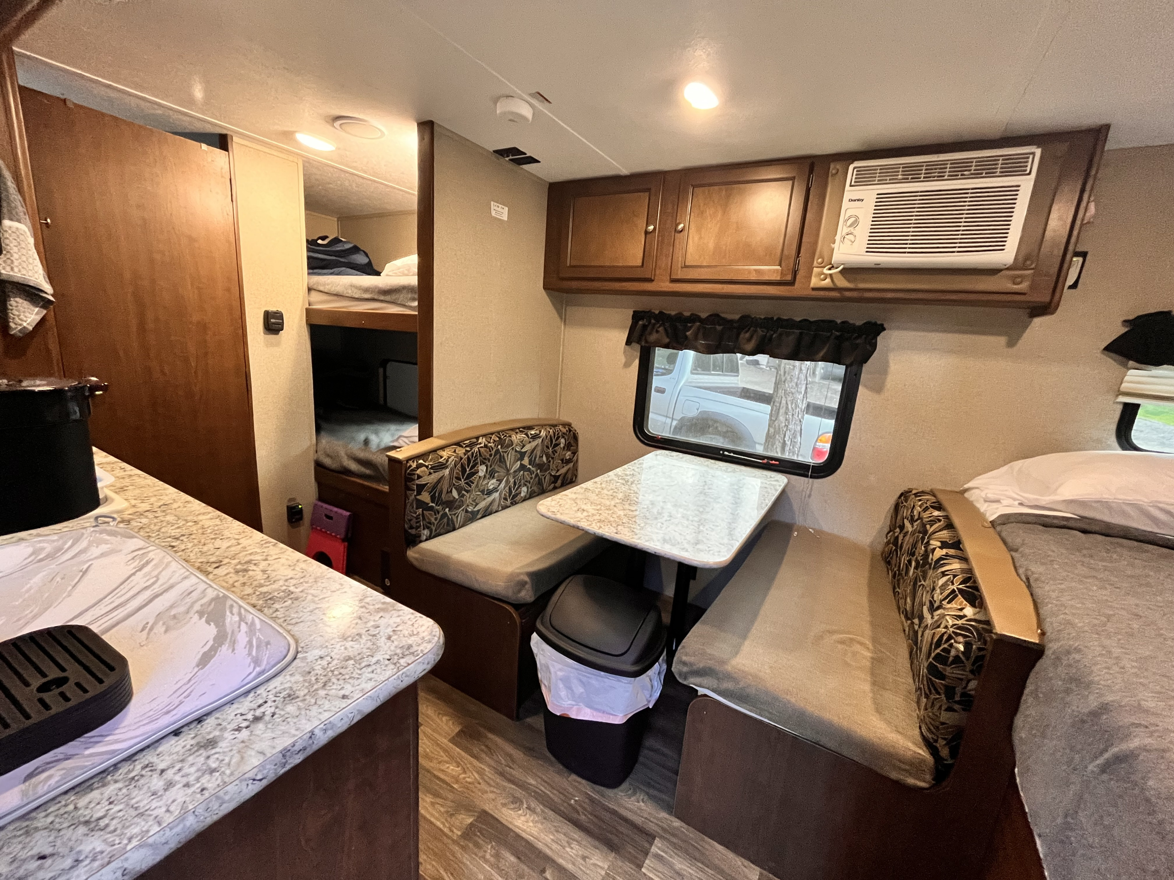 Cozy RV rental interior featuring a dinette, kitchen, bunk beds, and a main bed. Ideal compact living space for adventures.. Keystone RV Hideout 2017