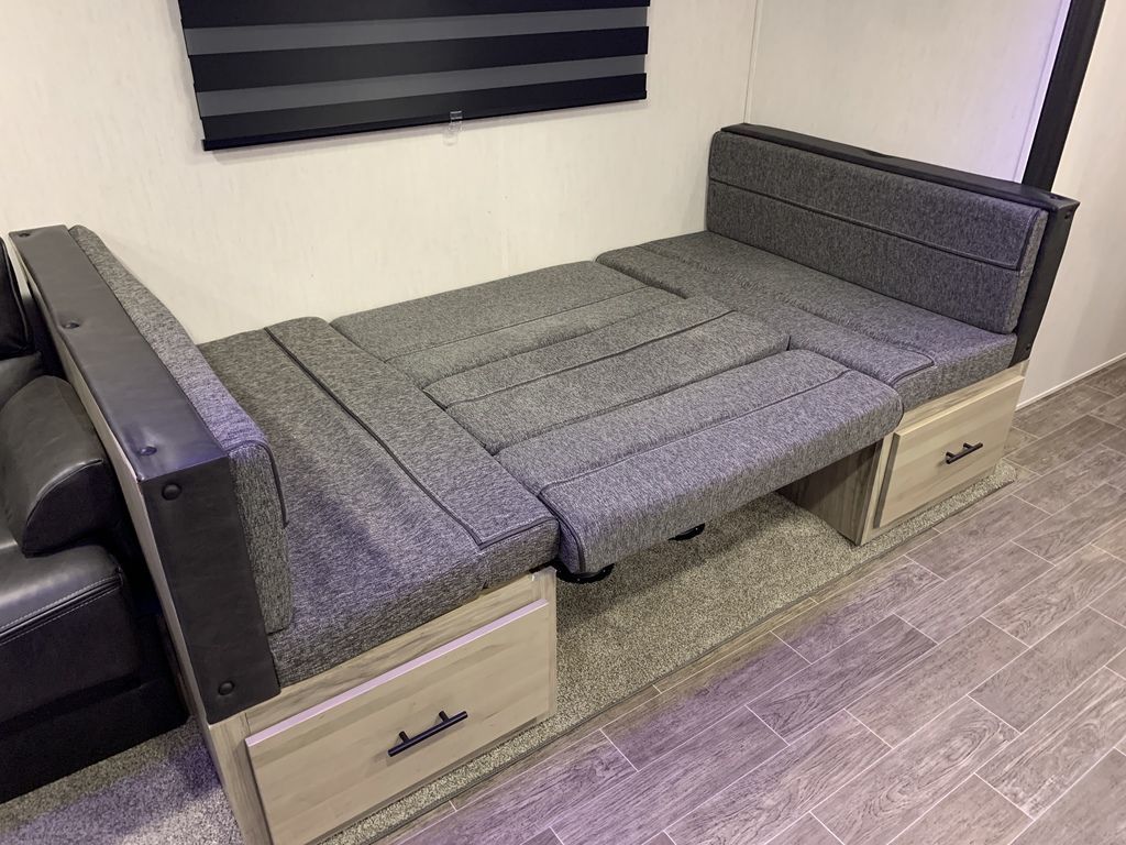 RV rental: Gray modular seating, partially extended as a bed, features built-in storage drawers below for travel.. Forest River Alpha Wolf 2022