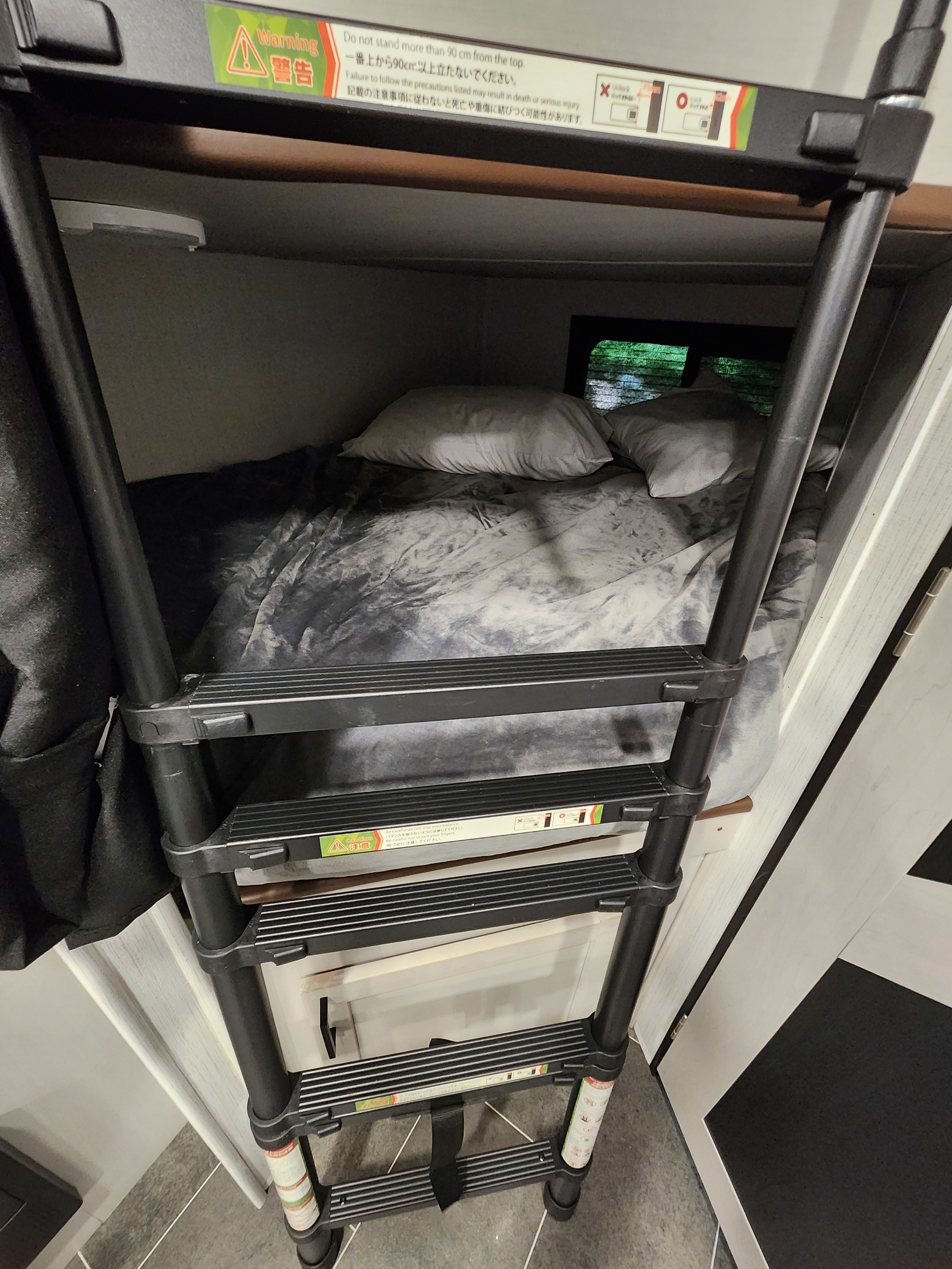 Inside an RV rental: a cozy bunk bed with a sturdy access ladder, displaying crucial safety warnings for use.. Heartland Mallard 2022