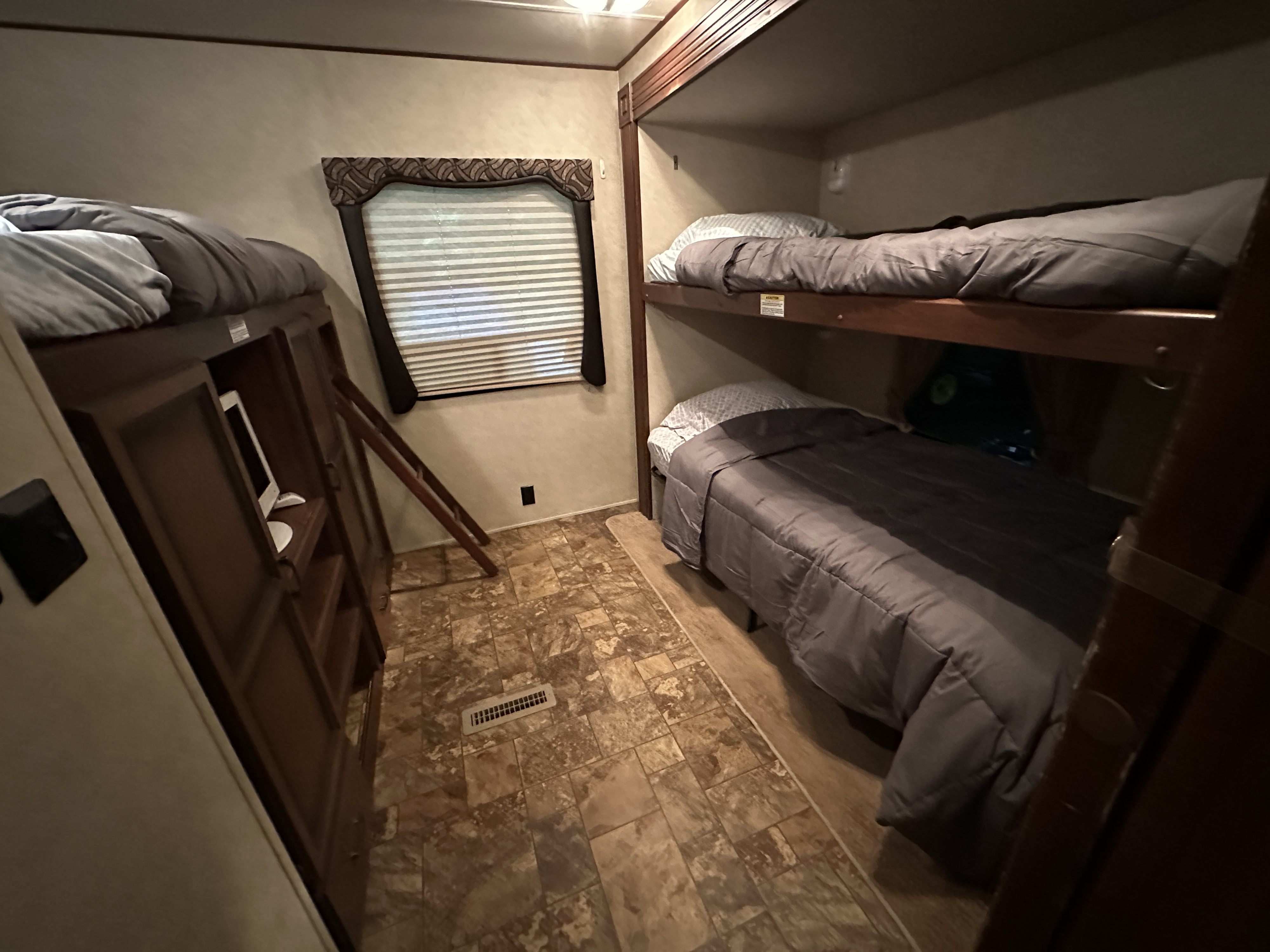 RV rental's cozy bunk room: three comfortable bunk beds, a window with blinds, and built-in storage. Ideal for families.. Crossroads RV Zinger 2012