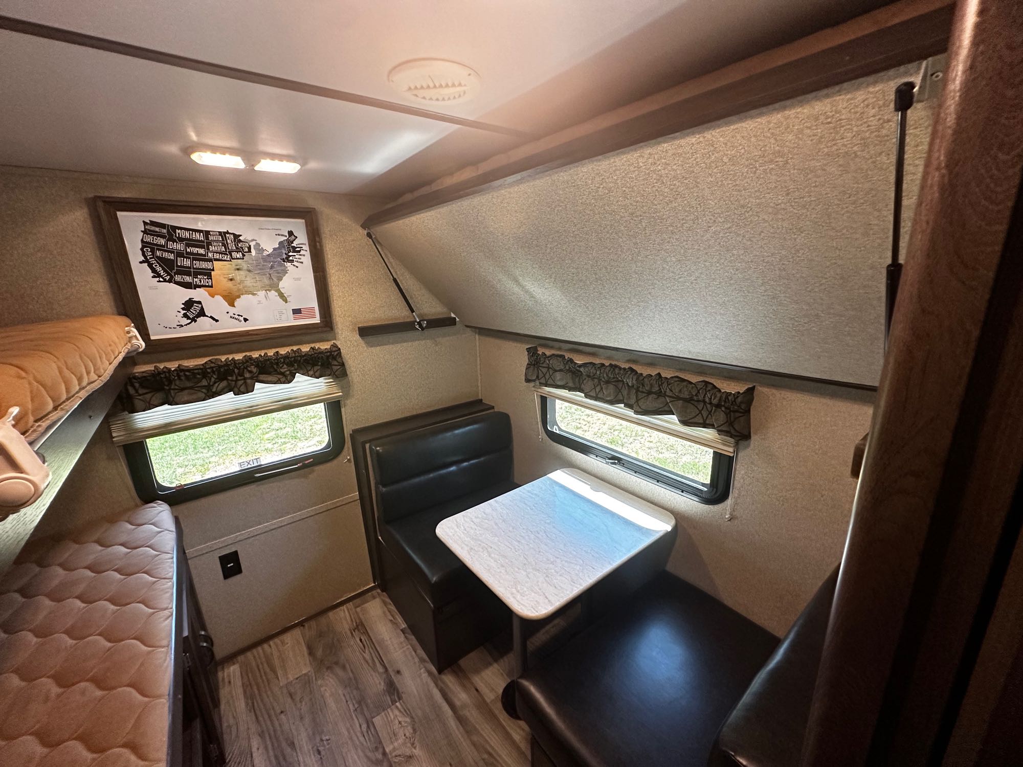 Cozy RV rental interior with bunk beds and dinette, perfect for family road trips. Features a US map for tracking adventures.. Keystone RV Outback Ultra-Lite 2018
