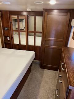Inside this RV rental: a clean white bed, rich wooden cabinets, and mirrored sliding doors create a comfortable bedroom space with storage.. Heartland Bighorn 2017