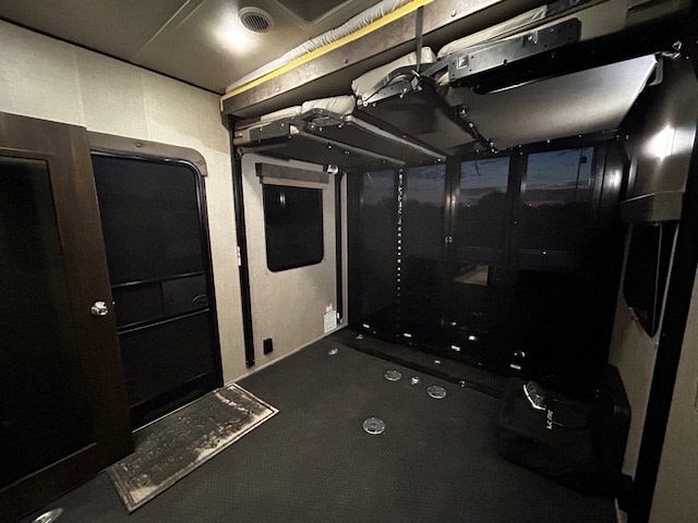 Spacious RV rental toy hauler interior. Shows garage area, fold-down beds, and rear ramp door with outdoor view.. Grand Design Momentum 2020