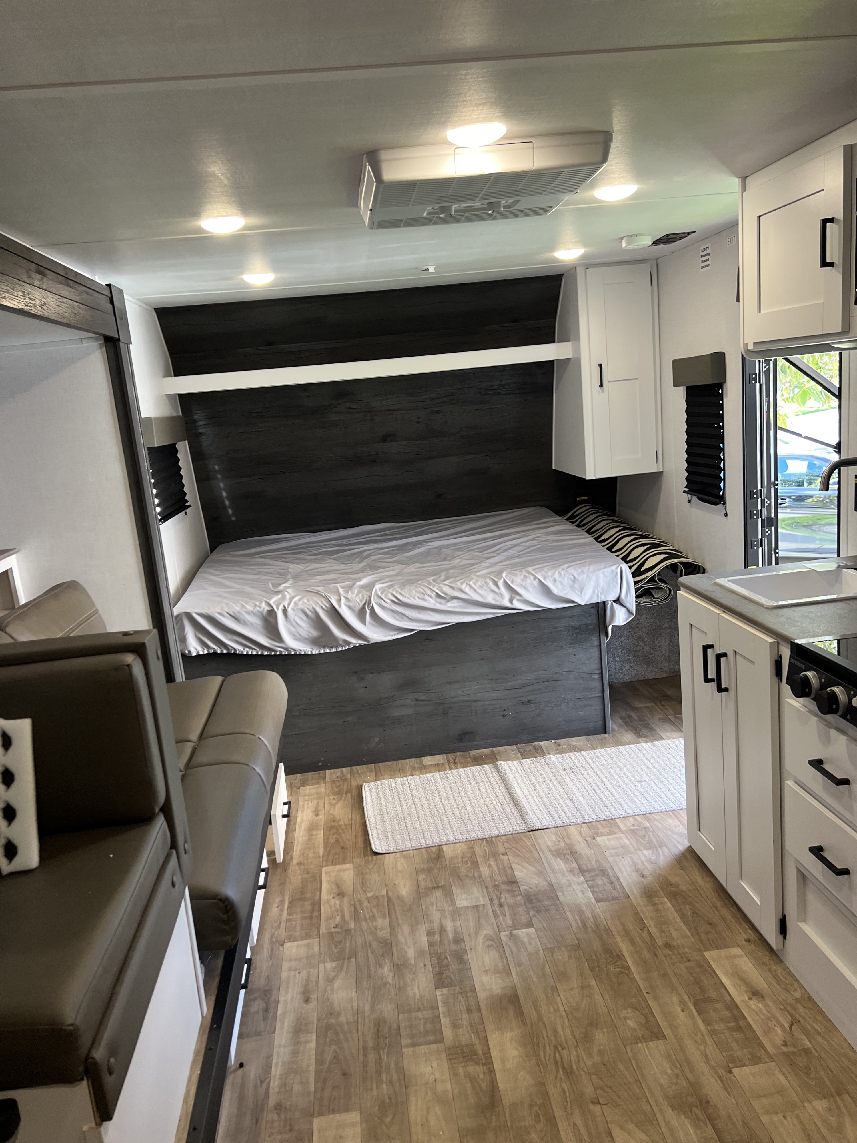 Spacious RV rental interior: bedroom, kitchen, and living area with modern decor and wood flooring.. Keystone RV Hideout 2023