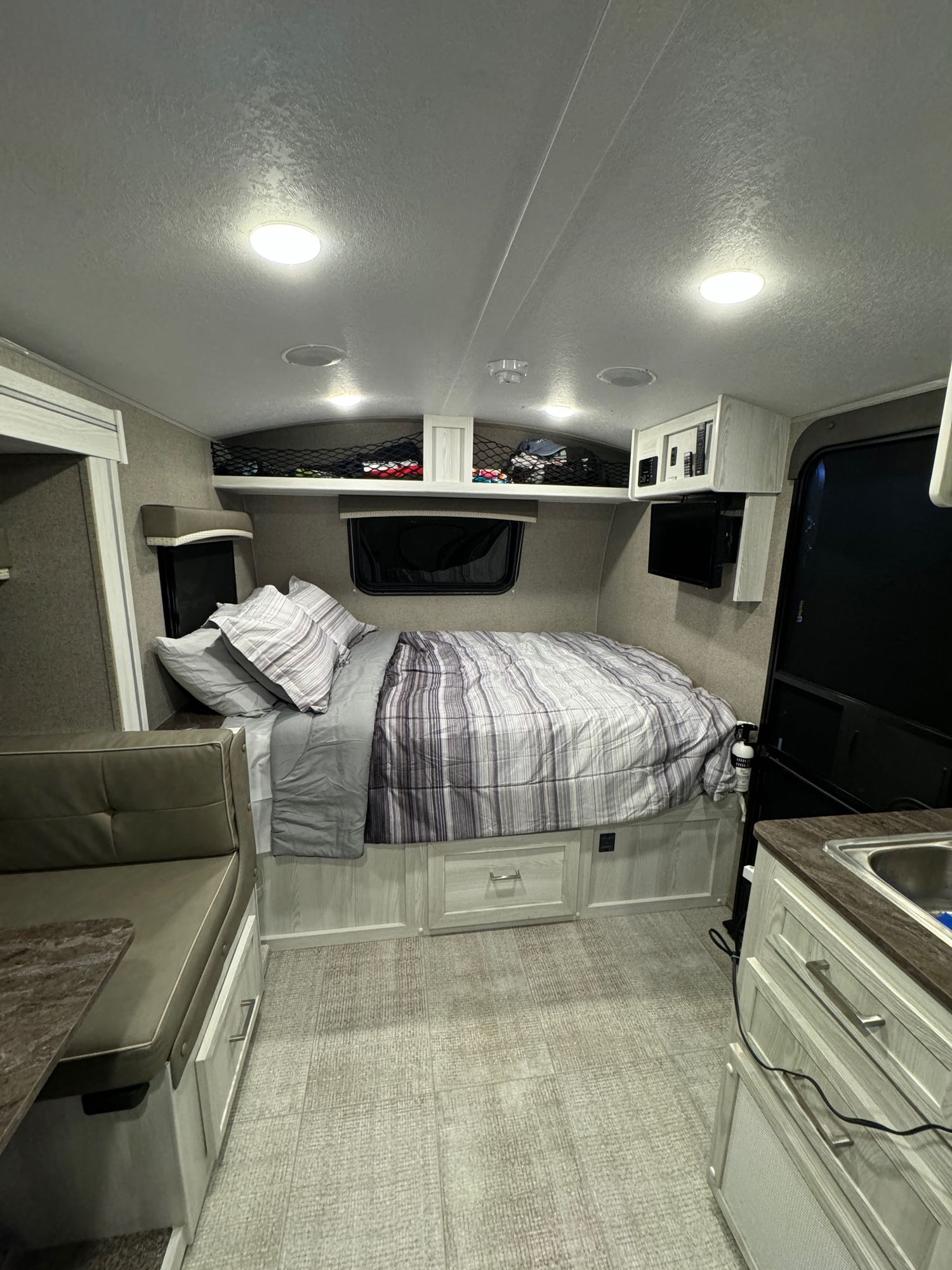 Bright RV rental interior showing a comfortable bed, compact dinette, and practical kitchen area.. Forest River Rockwood Geo Pro 2021