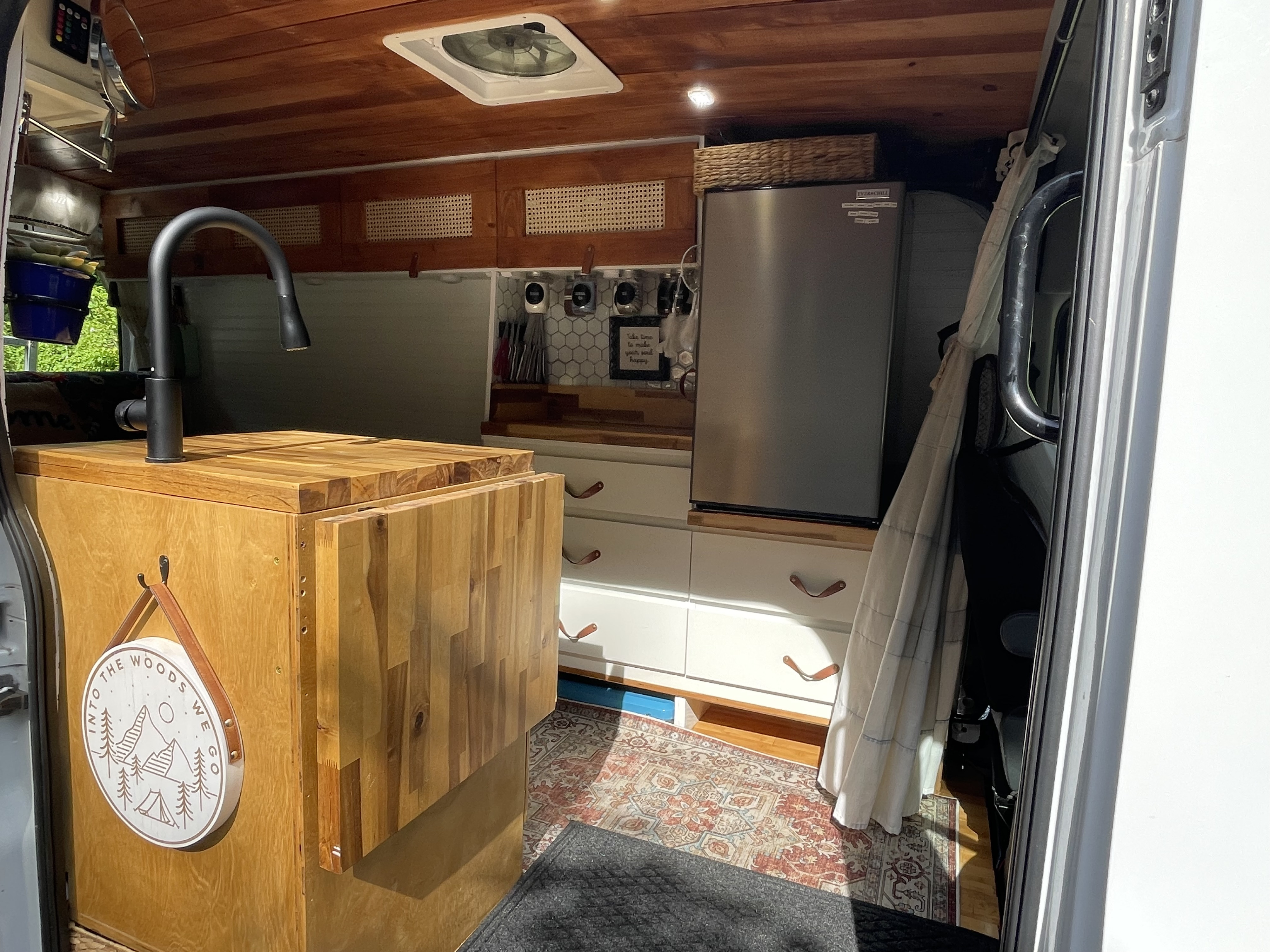 Inside an RV rental: a well-equipped mobile kitchen with wood details, fridge, and ample storage for adventures.. Ford Transit 2019