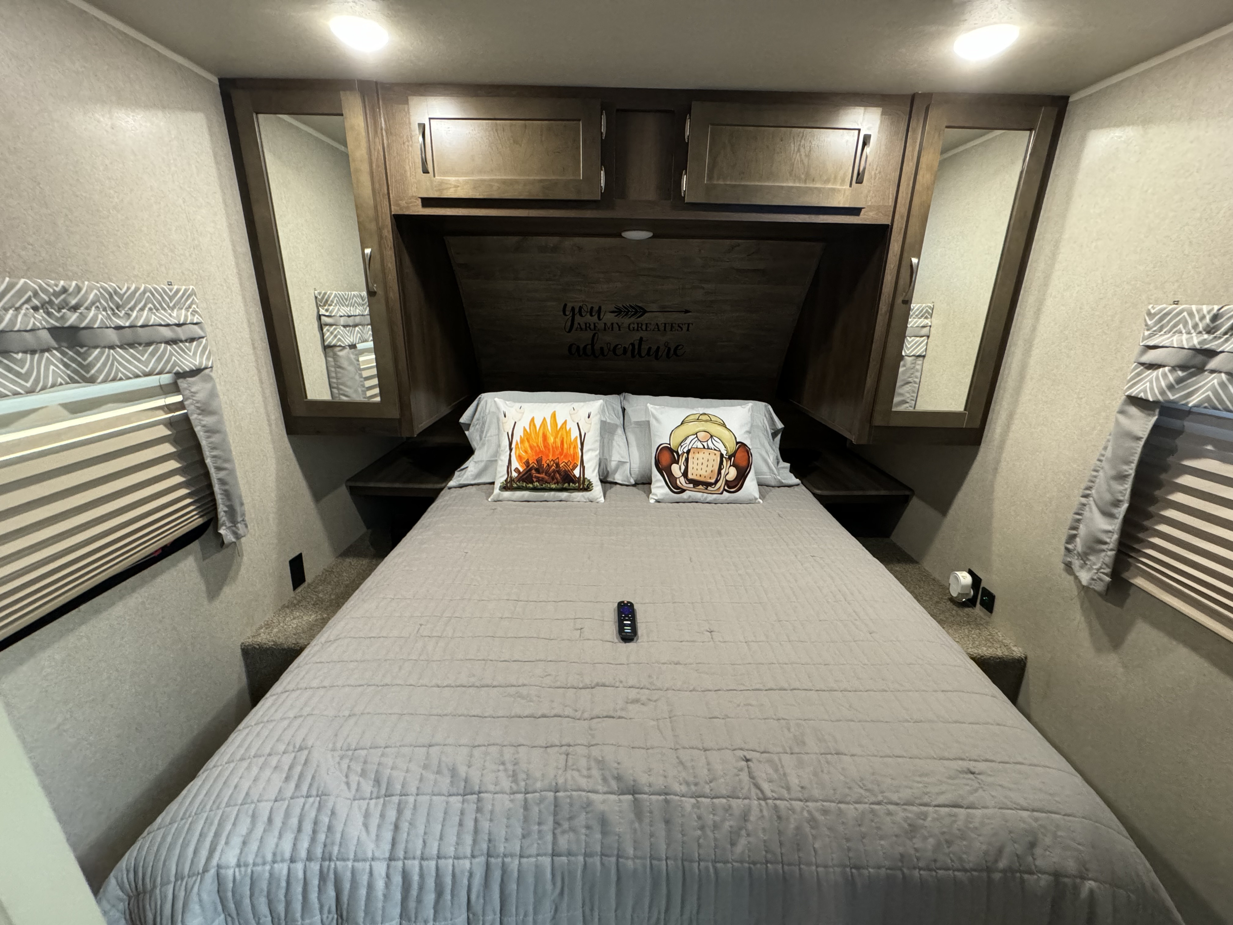 Inside a cozy rv rental, this bedroom features a comfortable bed with fun pillows, overhead storage, and mirrored closets.. Forest River Palomino Puma 2018