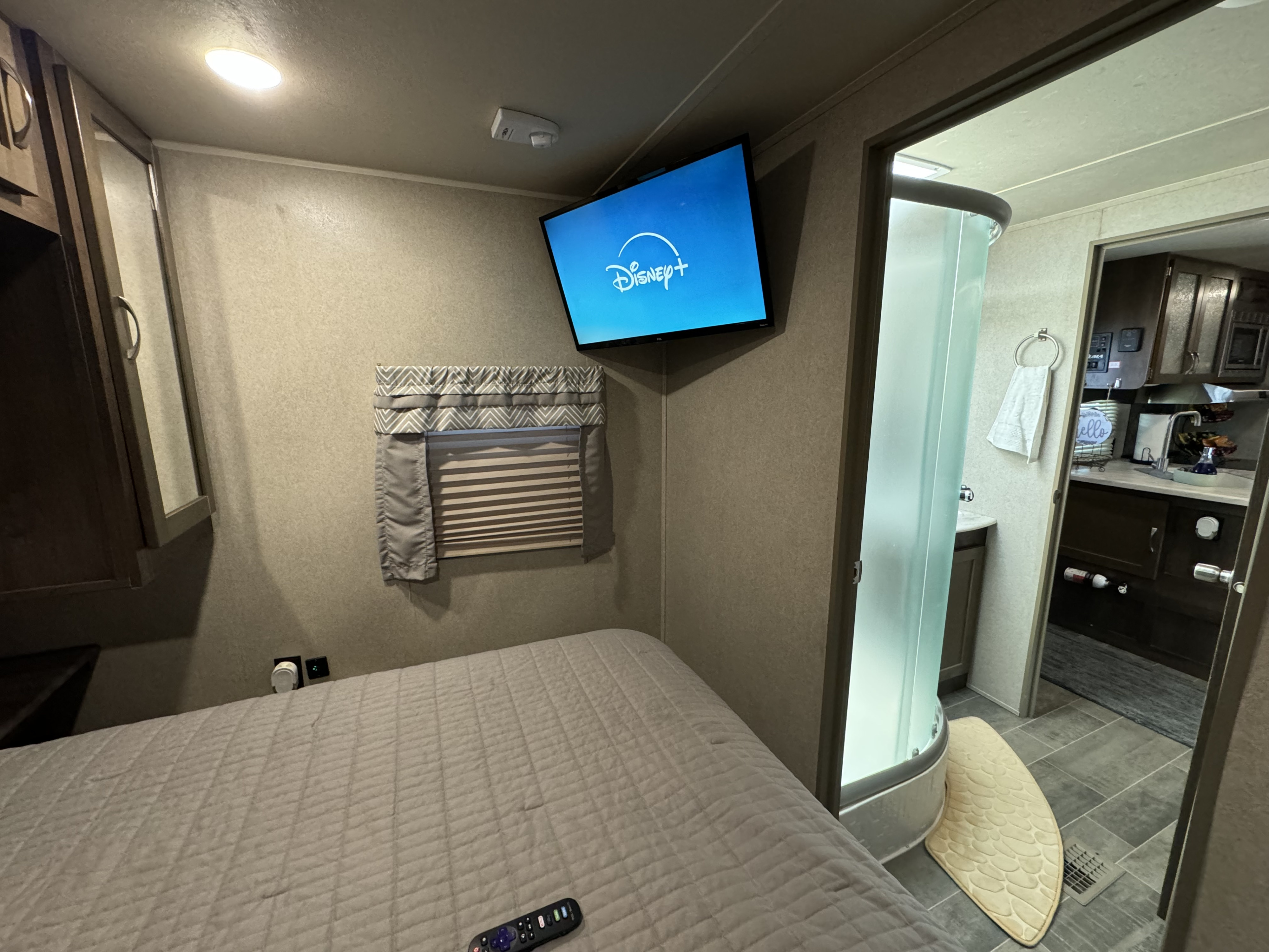 Compact RV rental bedroom with comfy bed, Disney+ TV, and en-suite shower. Perfect for on-the-go stays.. Forest River Palomino Puma 2018