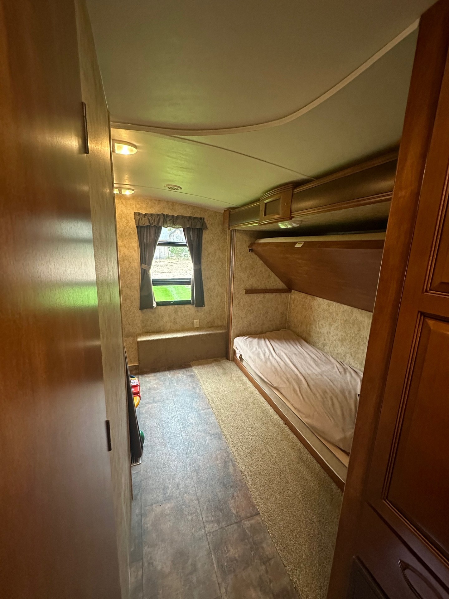 RV rental interior: A cozy bunk room with a window, built-in bench, and a lower bunk bed.. Keystone RV Bullet Premier Ultra 2012
