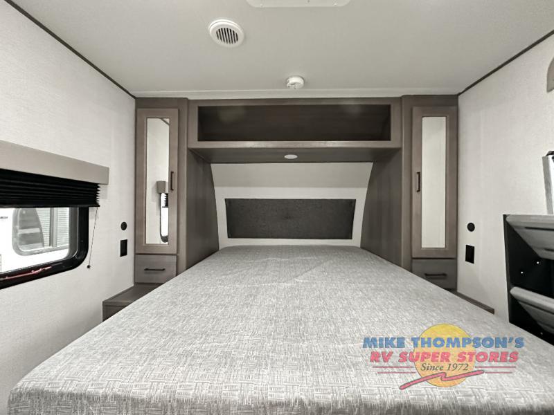 Inside an RV rental: a modern bedroom with a large bed, ample storage, window, and TV mount.. Grand Design Transcend Xplor 2024
