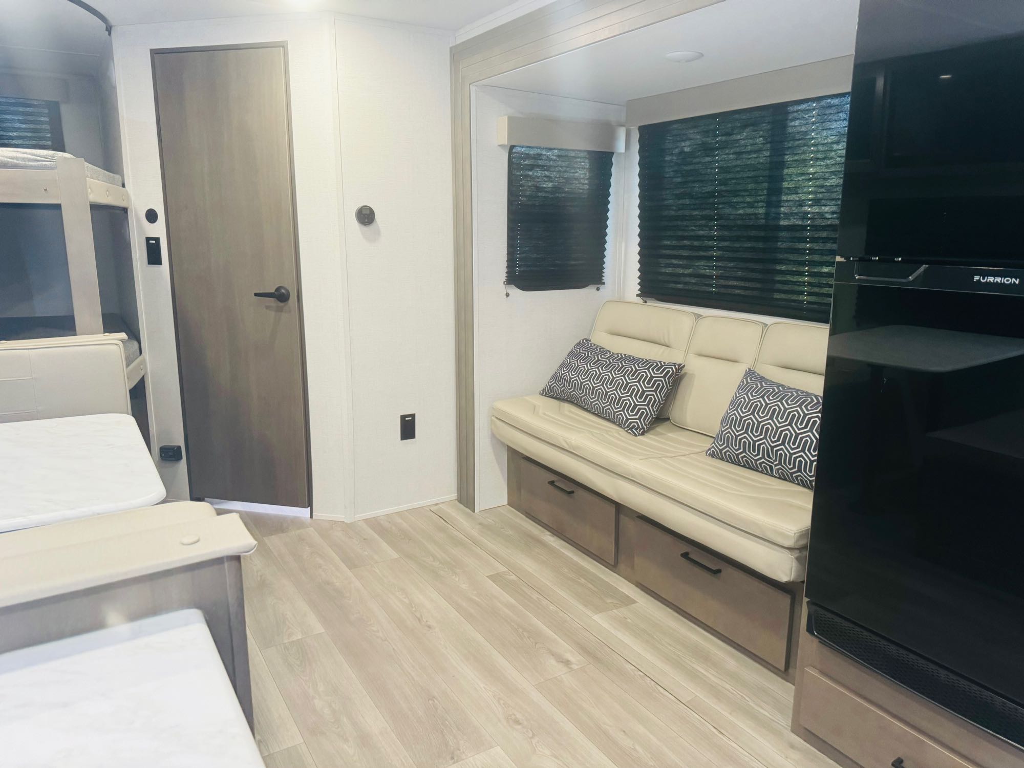 Explore this clean RV rental interior! Features include bunk beds, a cozy sofa with storage, and an entertainment unit.. Grand Design Transcend Xplor 2024