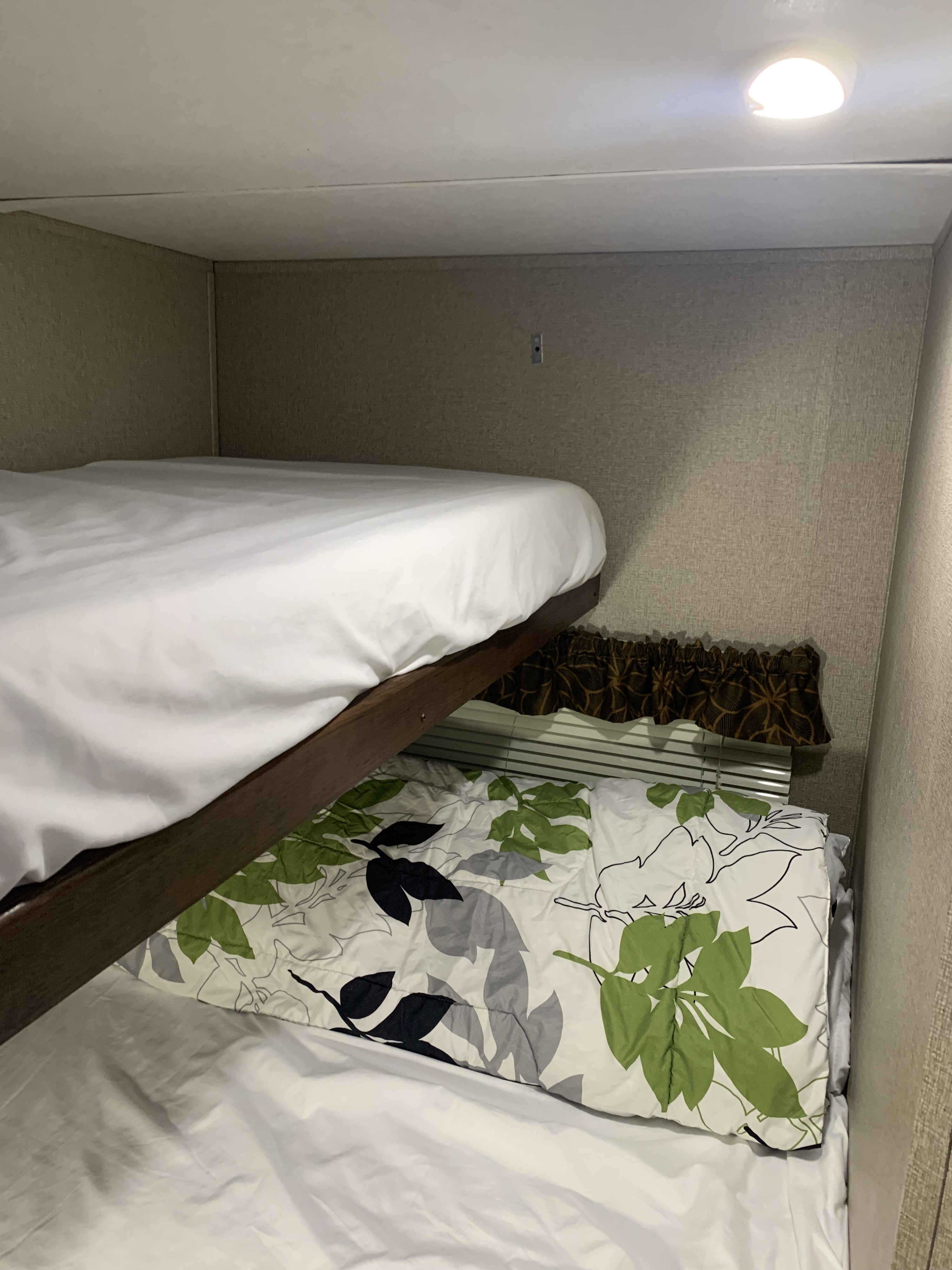 RV rental interior: Cozy bunk beds with white sheets and a leafy comforter in a compact space.. Keystone RV Hideout LHS Mini 2017