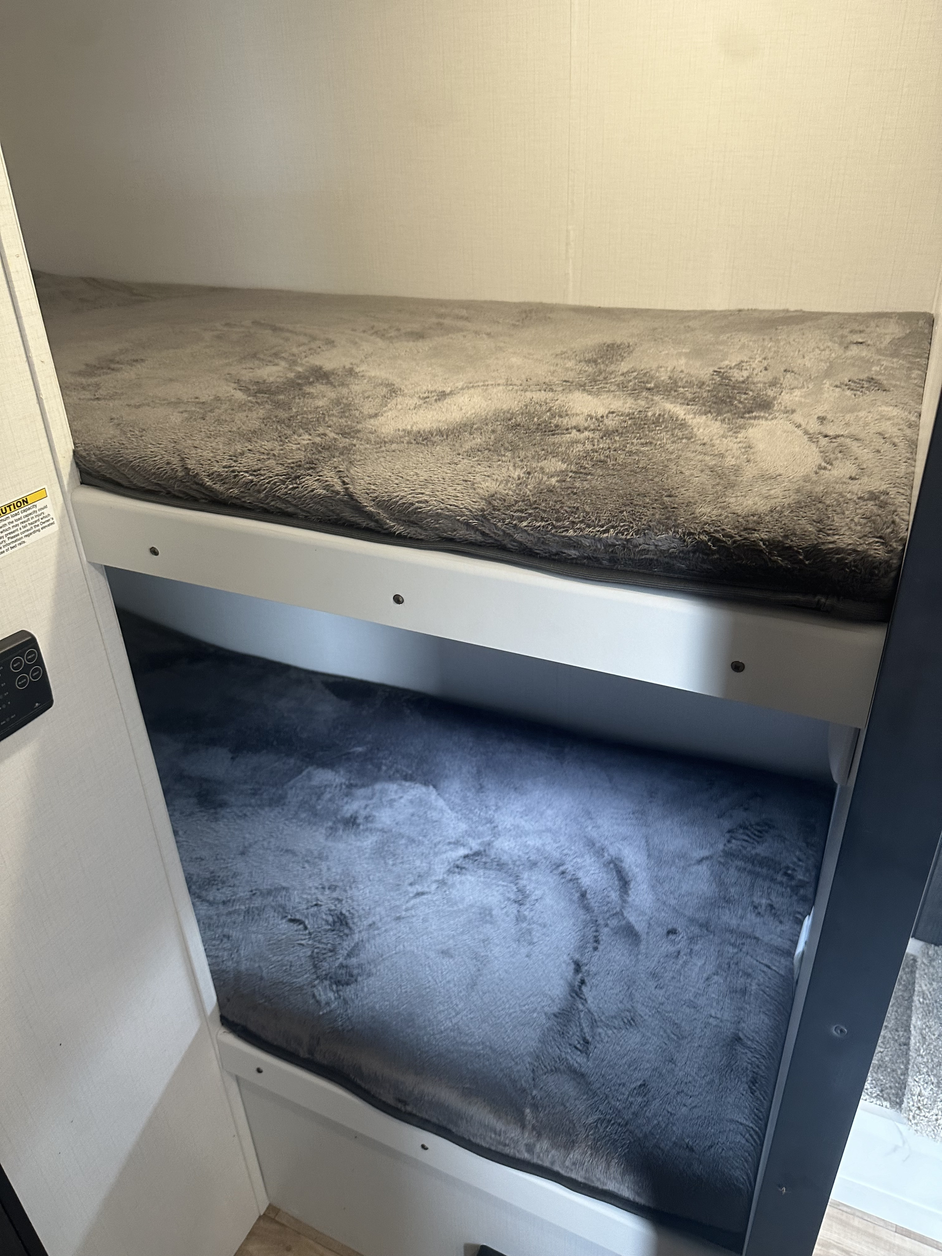 Cozy RV rental bunk beds with soft grey furry bedding. Perfect for family adventures in a compact interior.. Keystone Hideout 2022