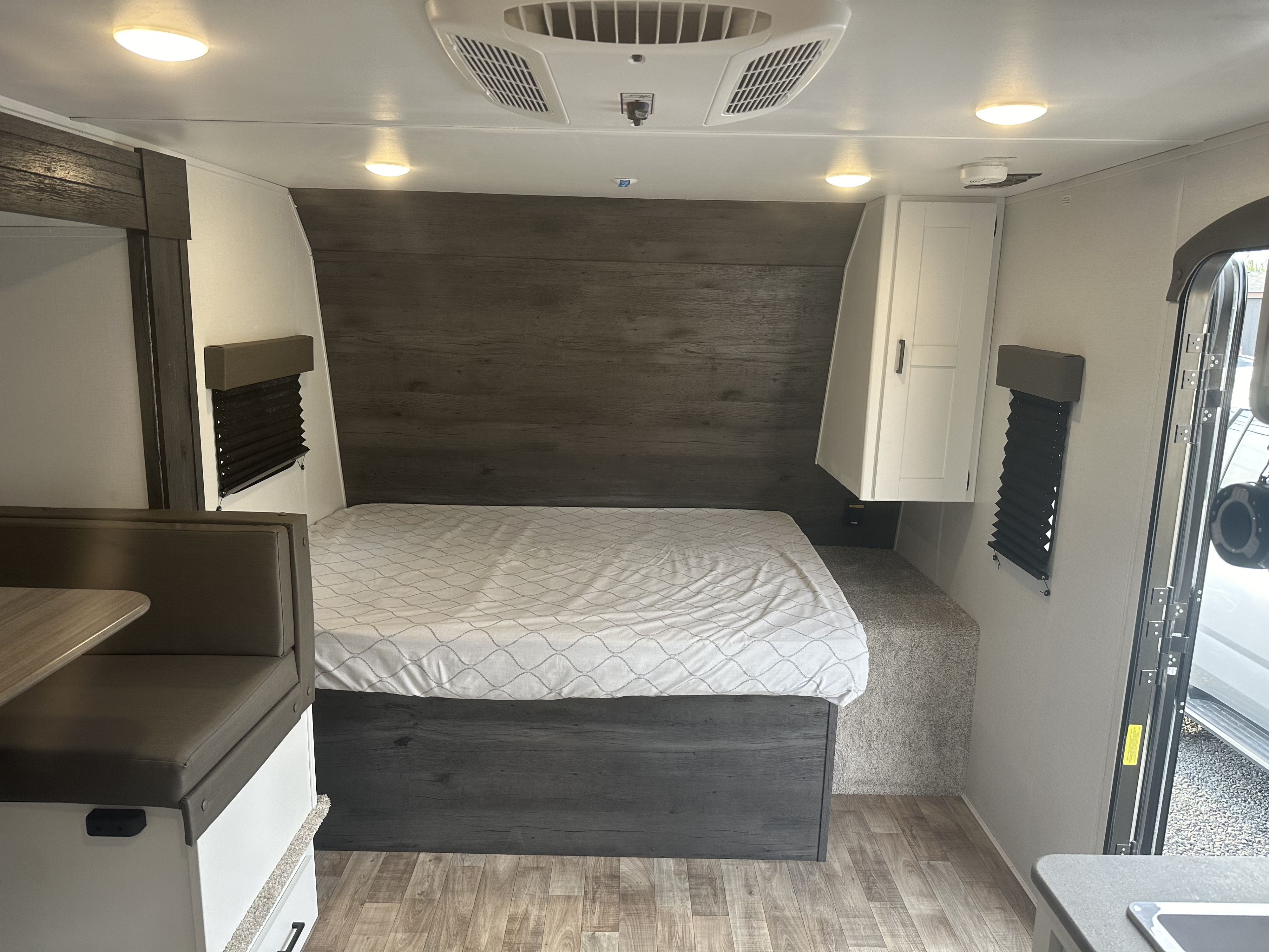 Interior of an RV rental showing a queen bed, dinette, ceiling AC, and kitchen counter. Bright, compact living space.. Keystone Hideout 2022