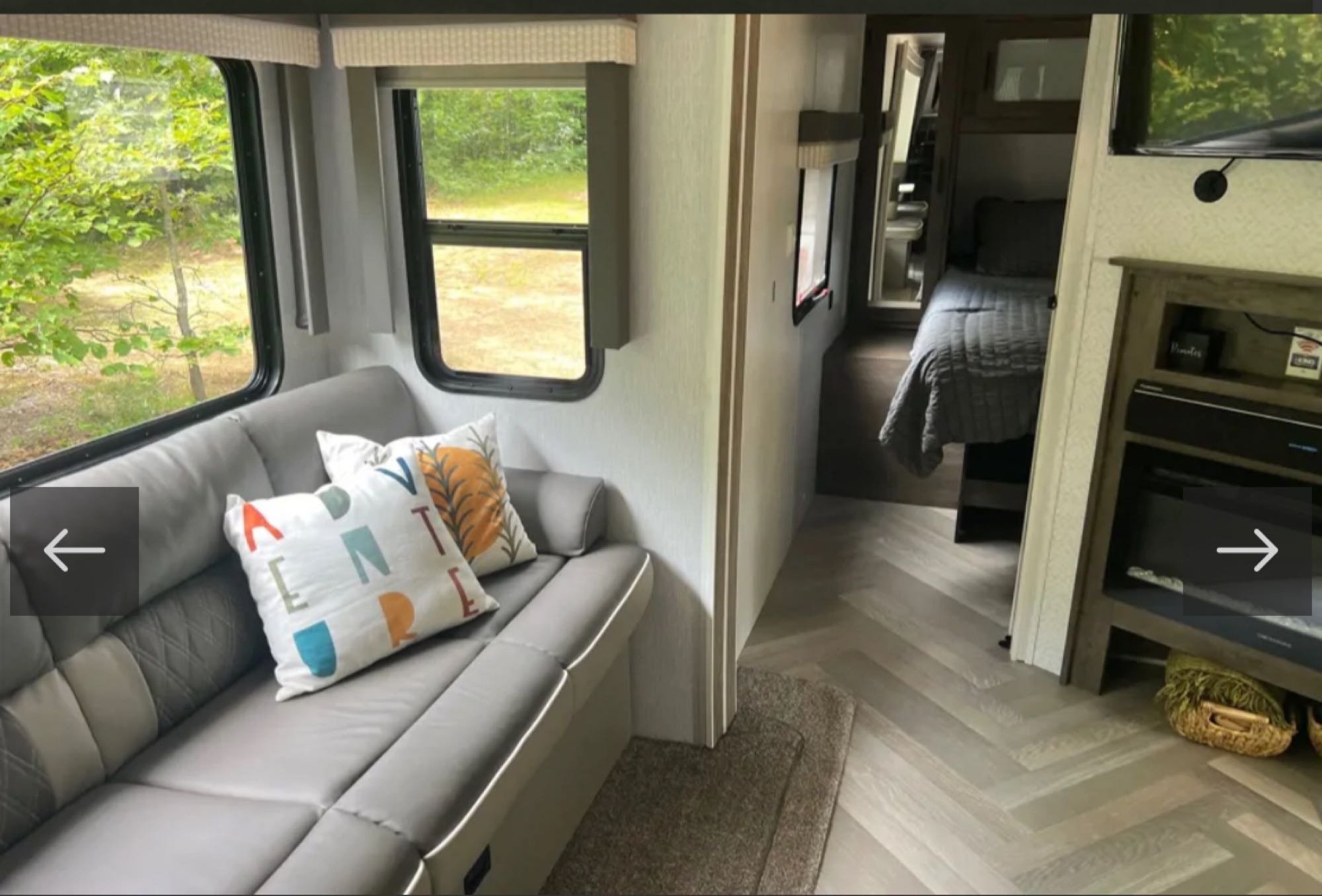 Spacious RV rental interior featuring a modern living area with sofa, nature views, and a cozy bedroom.. Forest River Wildwood 2022