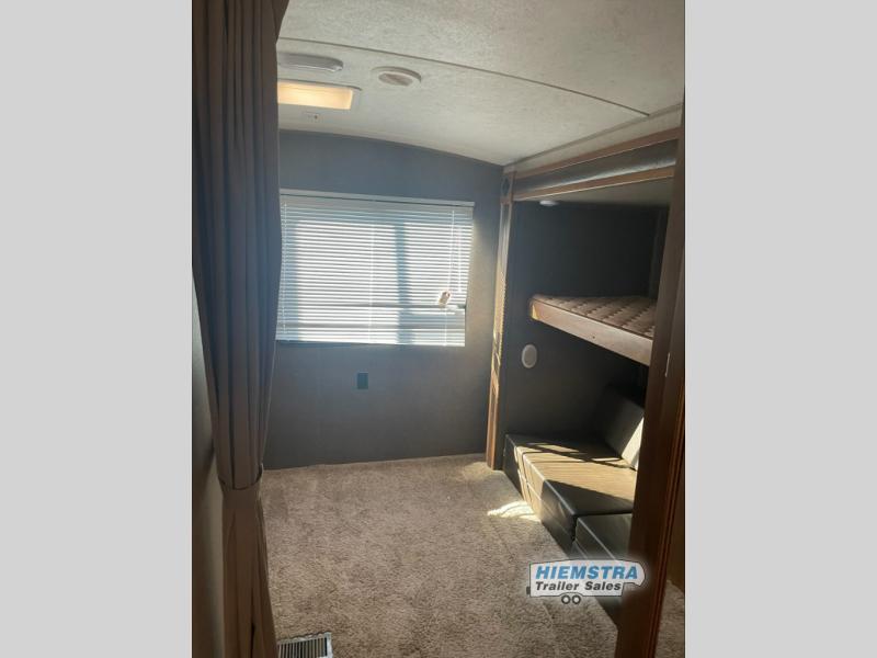 RV rental interior: Cozy bunk bed setup with seating below, large window, and carpeted floor for comfortable travel.. Keystone RV Springdale 2017