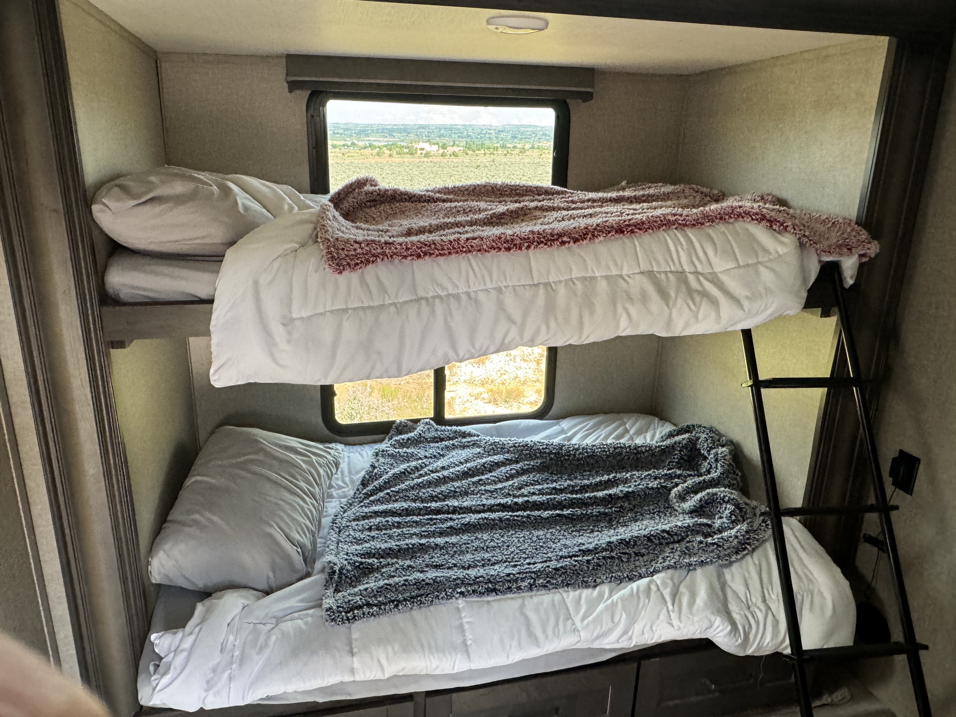 Cozy RV rental bunk beds with window views of arid landscape.. Grand Design Reflection 2021