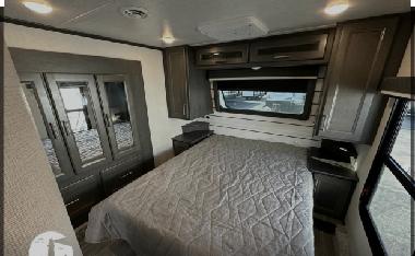 This RV rental offers a comfortable bedroom with a queen bed, mirrored wardrobe, and ample overhead storage.. Keystone Cougar 2021