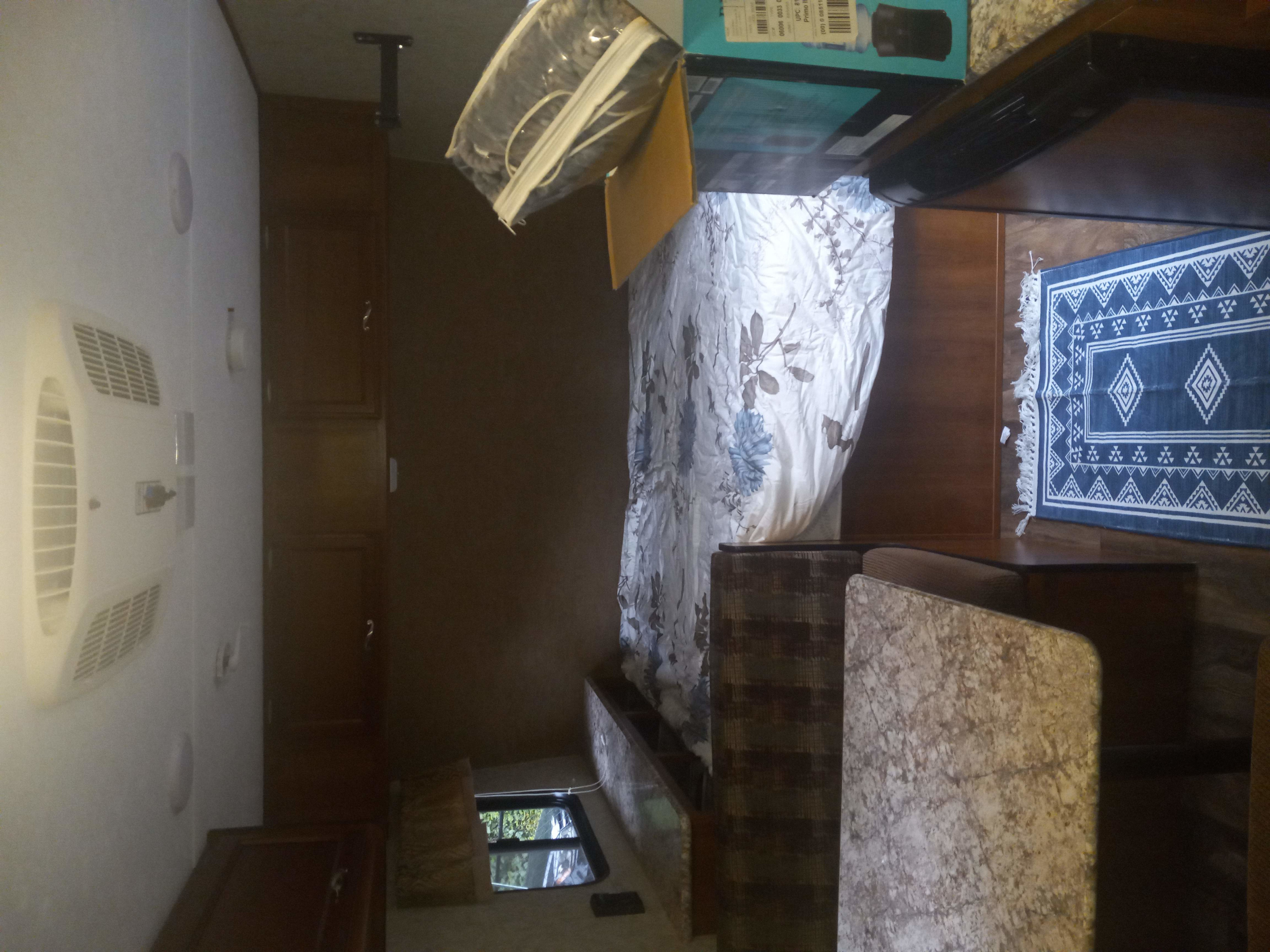 Cozy RV rental interior featuring a bed, dining booth, kitchen counter, overhead cabinets, ceiling AC, and a decorative rug.. Avenger Avenger Trailer 2016