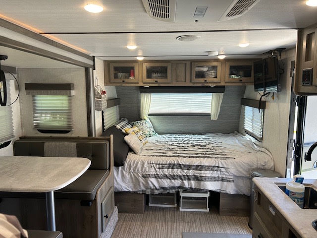Spacious RV rental interior featuring a cozy bed, dinette, and kitchen. Ideal for comfortable travel adventures.. Forest River Surveyor Legend 2021