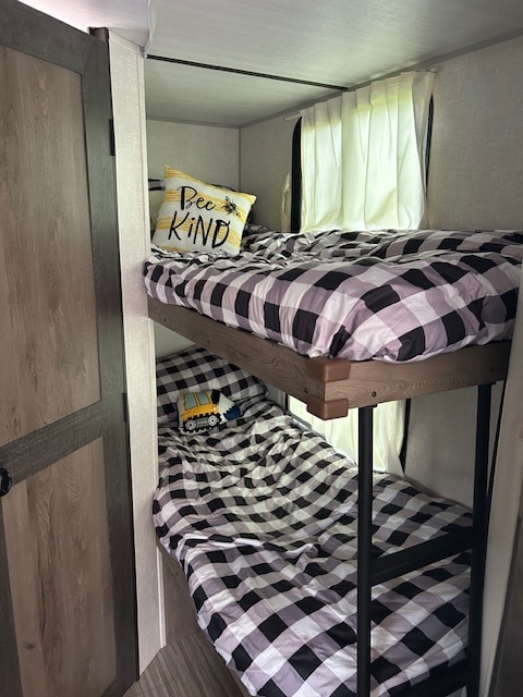 RV rental bunk beds: black & white plaid bedding with 'Bee Kind' & construction pillows for cozy sleeps.. Forest River Surveyor Legend 2021