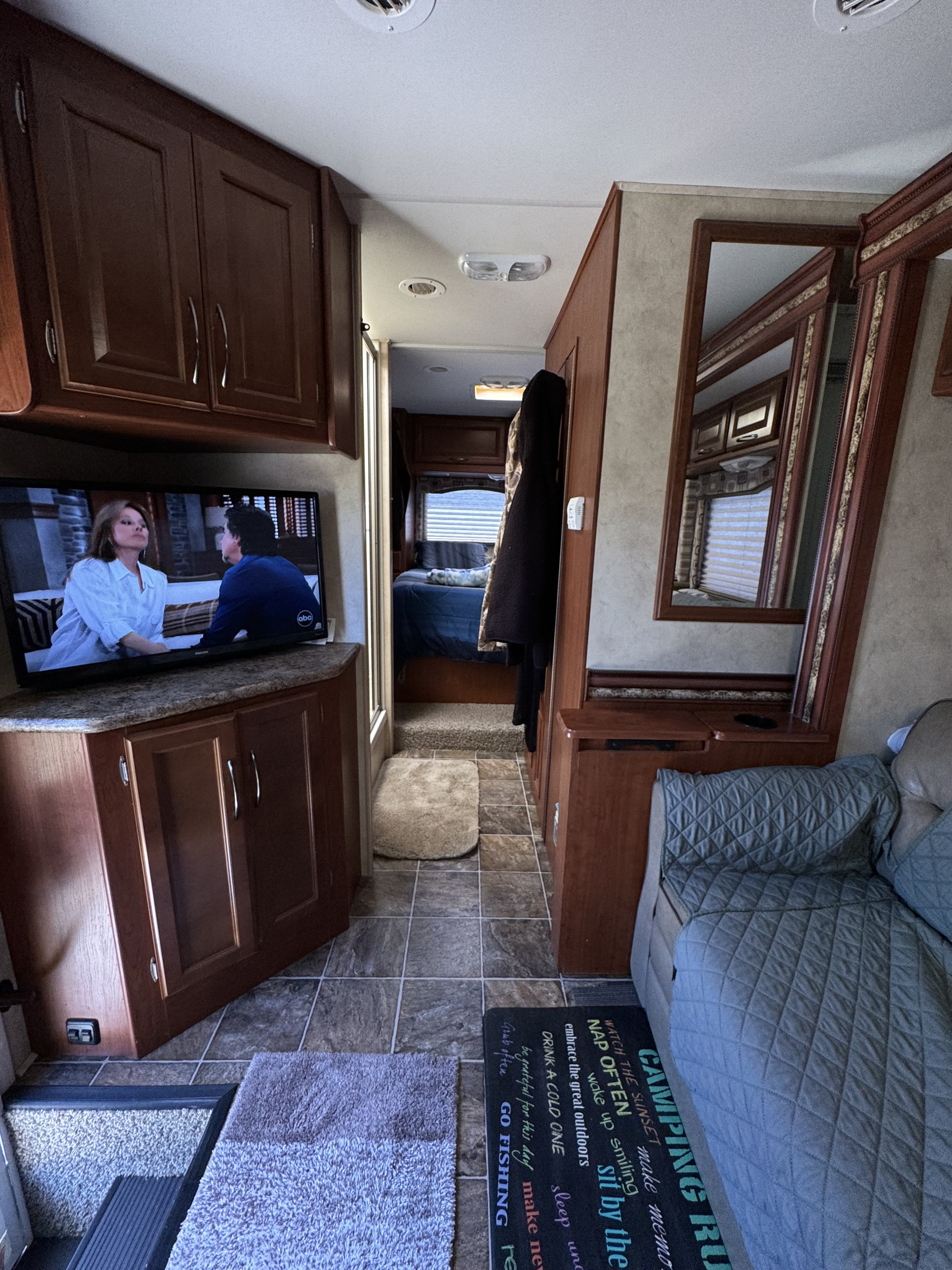 This RV rental's comfortable interior features a living area with TV, storage, and a cozy bedroom hallway visible ahead.. Thor Motor Coach Four Winds 2013
