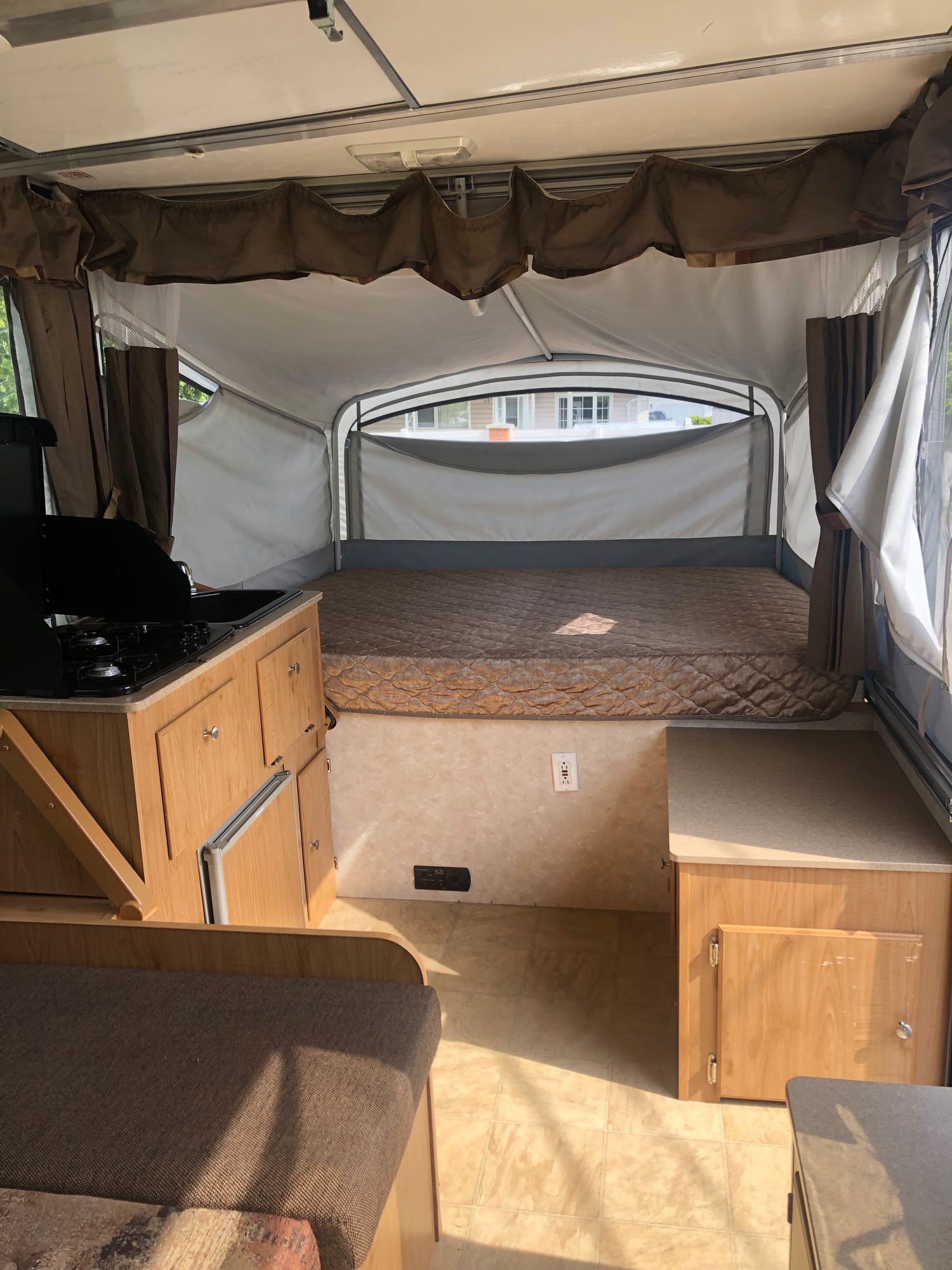 Pop-up RV rental interior: bed, compact kitchen with stove/sink, and seating. Plan your adventure!. Fleetwood santa fe 2008